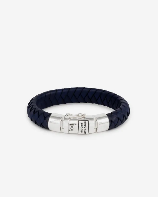 De Ben Leren armband in stijlvol navy is een krachtige interpretatie van de iconische Ben-schakel. Vervaardigd uit premium leer en afgewerkt met de kenmerkende sterling zilveren sluiting, belichaamt deze armband de essentie van Buddha to Buddha: kracht, moed en vakmanschap. Ontworpen in Amsterdam en met toewijding handgemaakt in Zuidoost-Azië, vormt deze armband een naadloze aanvulling op je zilveren Buddha to Buddha collectie. Deze lederen Ben armband is groter dan de Ben Small leer. Welk avontuur ga jij aan met deze armband?