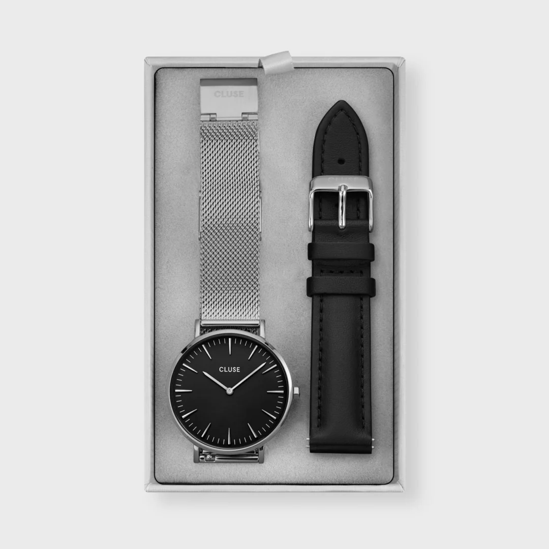 Een statement in zilver. Deze prachtige CLUSE geschenkdoos voor dames combineert ons iconische zilverkleurig Mesh Boho Chic-horloge met een extra zwarte leren band. Het delicate ontwerp van dit horloge maakt het het perfecte accessoire voor een modieus en toch subtiel resultaat. Het CLUSE Boho Chic-horloge voor dames heeft een kast van 38 mm, een zwarte wijzerplaat en een zilverkleurig mesh-band. De band is eenvoudig te verwisselen met de 18 mm zwarte leren band met zilverkleurig details. Stijl je dag met elegant zilverkleurig mesh band , of ga voor klassiek zwart leer.
