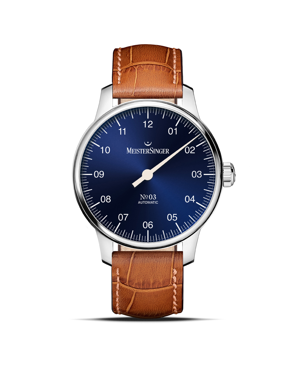 Dit schitterende horloge met één wijzer laat ons de tijd beleven op een stressvrije en meer ontspannen manier - ze geven ons een gevoel van vertraging. Als zus van de oer-MeisterSinger N°01 zijn ook bij de N°03 alle vormgevingsdetails terug te zien die tot op de dag van vandaag de hele collectie bepalen: de zakelijke typografie met consequent tweecijferige uur aanduidingen van 01 tot 12, de streepjeshiërarchie rond de wijzerplaat en de uurwijzer met naaldpunt. Duidelijker, eenvoudiger en ingetogener kan men een horloge niet vormgeven. In deze uitvoering draagt ze een glanzend witte wijzerplaat met gouden uur aanduiding en blauwe en zwarte contrasten bij de indexen.