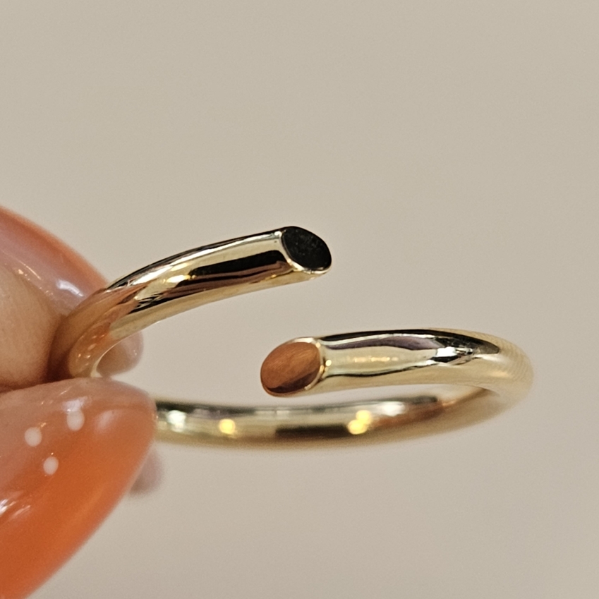 Deze prachtige ring is gemaakt van 14 karaat goud en heeft open uiteinden voor een unieke uitstraling. De ring is maat 18.5 en past perfect bij elke gelegenheid. Draag hem alleen of combineer hem met andere sieraden voor een gelaagde look. De ring is tijdloos en elegant, een must-have voor elke sieradencollectie. Bestel hem nu en voeg wat glans toe aan je outfit!