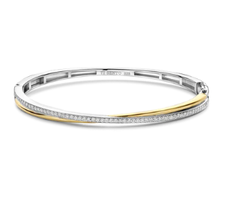 Laat je onderdompelen in een wereld van tijdloze elegantie met deze TI SENTO vergulde zilveren bangle armband 23045ZY. Gemaakt van 925 sterling zilver, beschikt deze armband over twee verstrengelde banden: de ene is bedekt met een stralende goudkleur, wat een vleugje warmte en luxe toevoegt, terwijl de andere band is versierd met een fonkelende pavé van witte cubic zirconia-stenen die een schitterend effect creëert. De contrasterende texturen en kleuren maken dit tot een visueel opvallend sieraad; een perfecte fusie van klassiek en eigentijds design. Versterk je dagelijkse look met dit verfijnde accessoire. Draag het alleen voor een gedurfde statement of combineer het met andere TI SENTO armbanden voor een persoonlijke touch. Met zorg vervaardigd voor gevoelige huid, garandeert deze nikkelvrije en hypoallergene armband blijvend comfort en kwaliteit.
