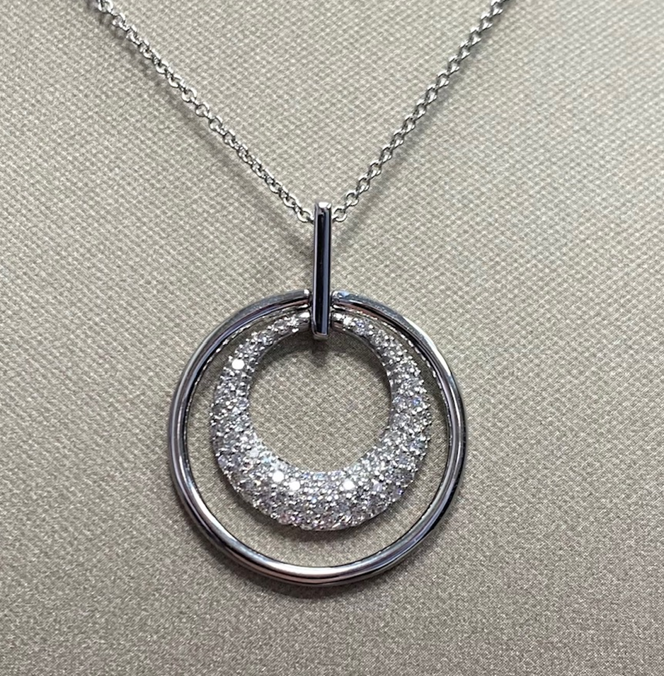 14 Karaat witgouden fantasie hanger gemaakt van 2 in elkaar geplaatste cirkels met briljant. Diameter 20 mm. briljant 0.42 crt H/SI. 