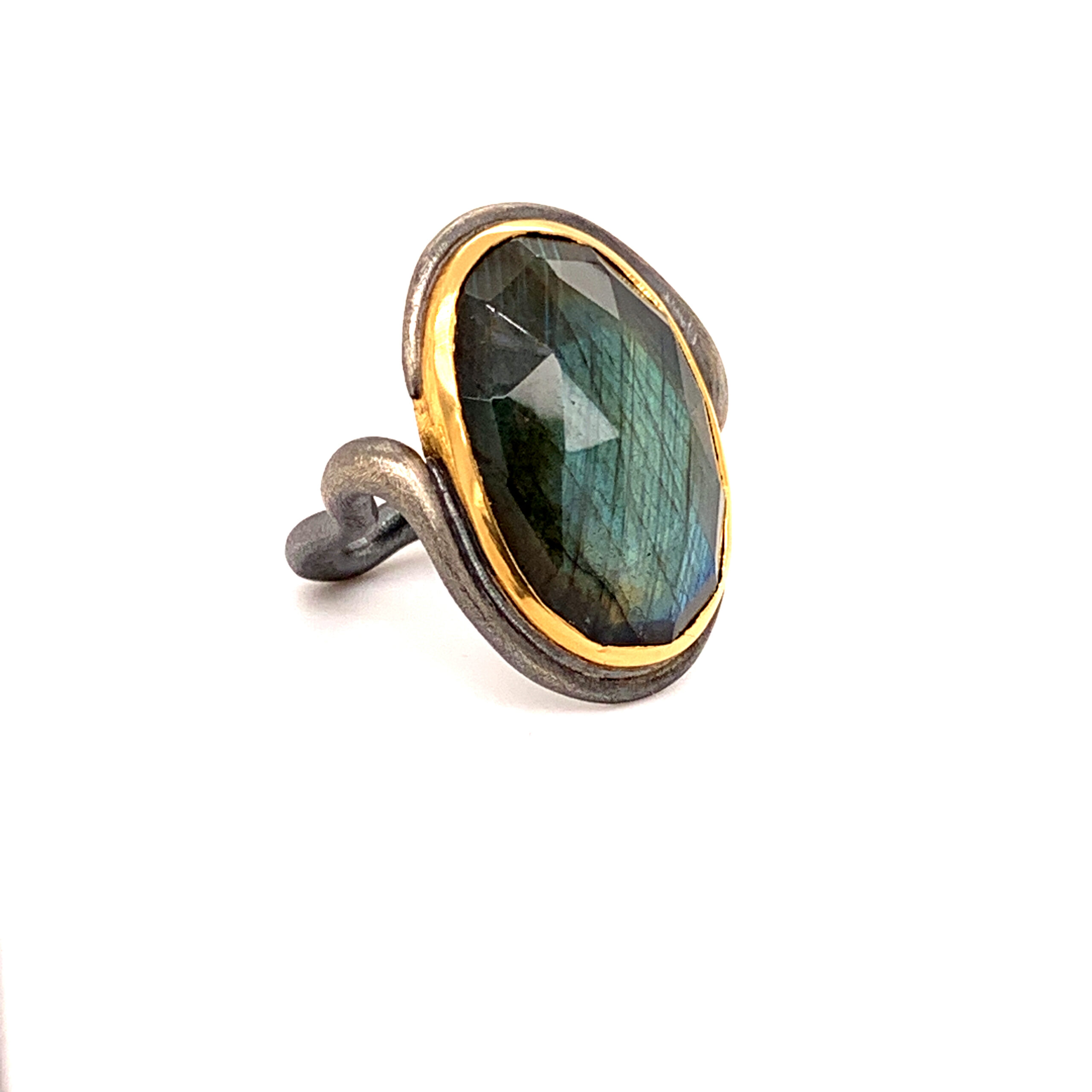 Der Labradorit - geheimnisvoll, changierend, mit dem mystischen Schimmer des Nordens. Ein Ring, zum Eintauchen schön, hier golden eingefasst und gehalten von organischen Formen, die sich sinnlich um den Finger schließen.

Ring, geschwärztes Silber und Gold 900, großer facettierter Labradorit, Größe 59, Größenänderung bei Bedarf inklusive