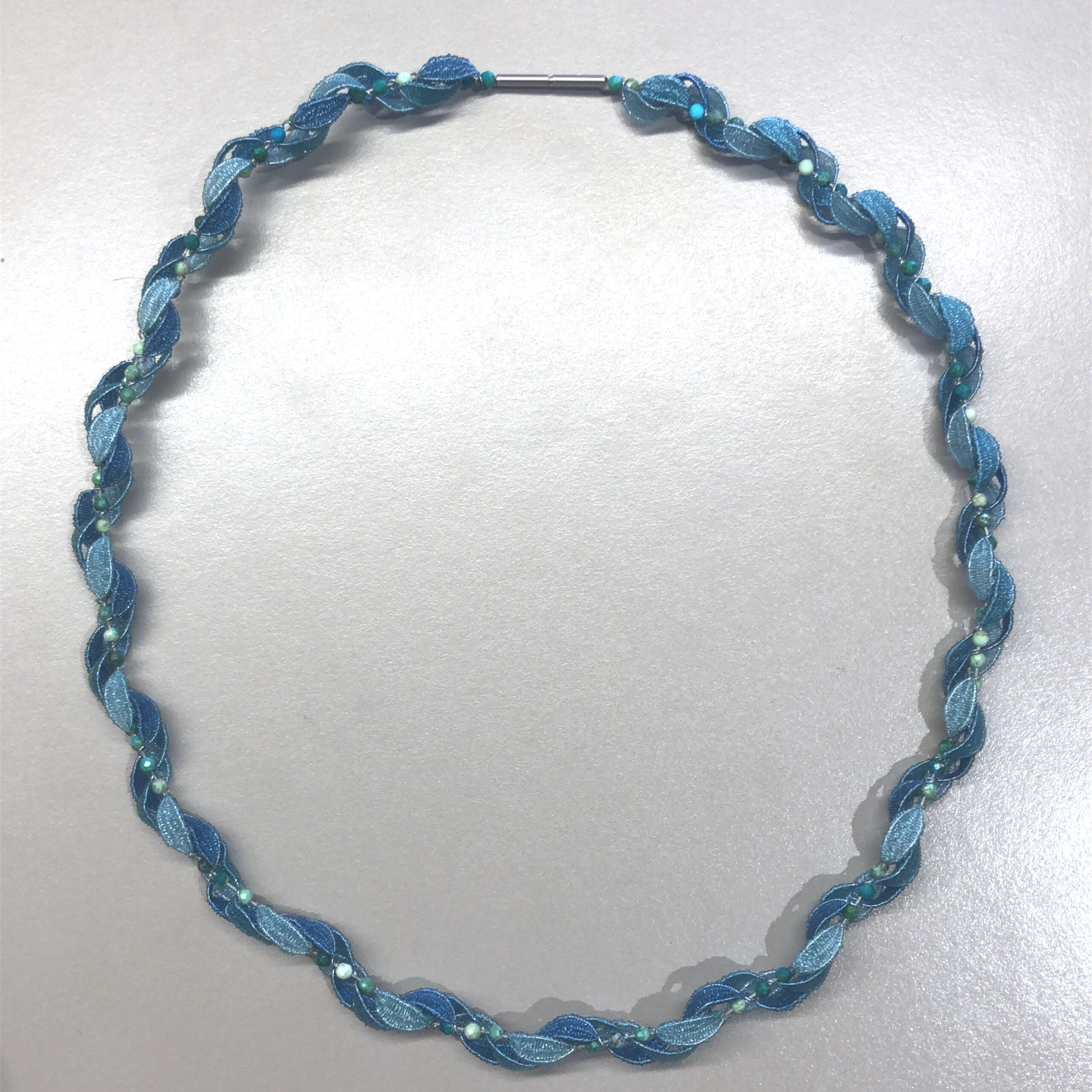 Handwerklich spektakulärer Halsschmuck. Hauchfein geklöppelte Segmente aus  Nylon in unterschiedlichen Blautönen, gedrehte Stahlseilstruktur. Länge 44cm

UNIKAT
Entwurf und Fertigung Stefanie Kölbel