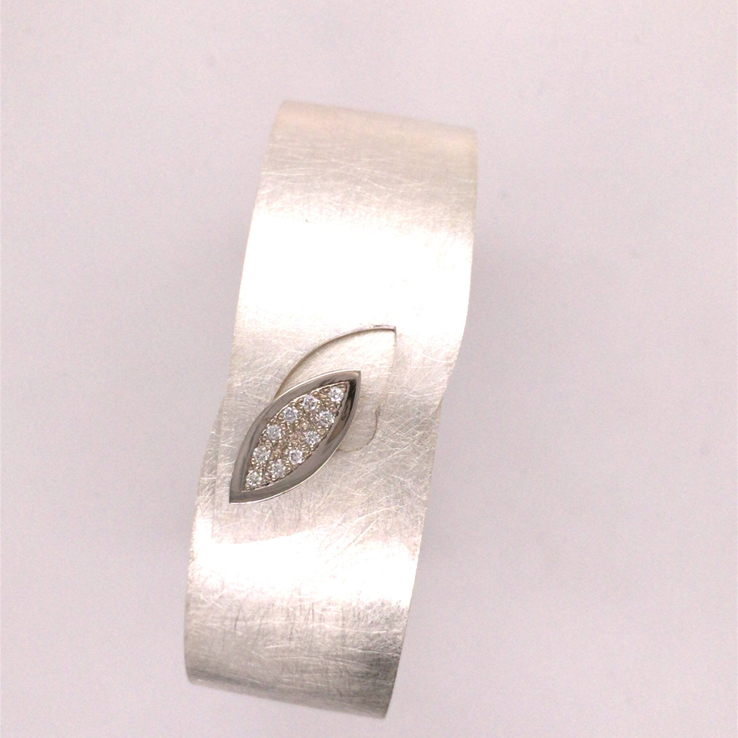 Armspange gearbeitet in Silber, mit 10 Brillanten. Über die Navette Fassung wird die Armspange geöffnet und geschlossen. Das Navette ist gearbeitet in PD/ WG. Breite 2 cm, Durchmesser 6,5 cm.