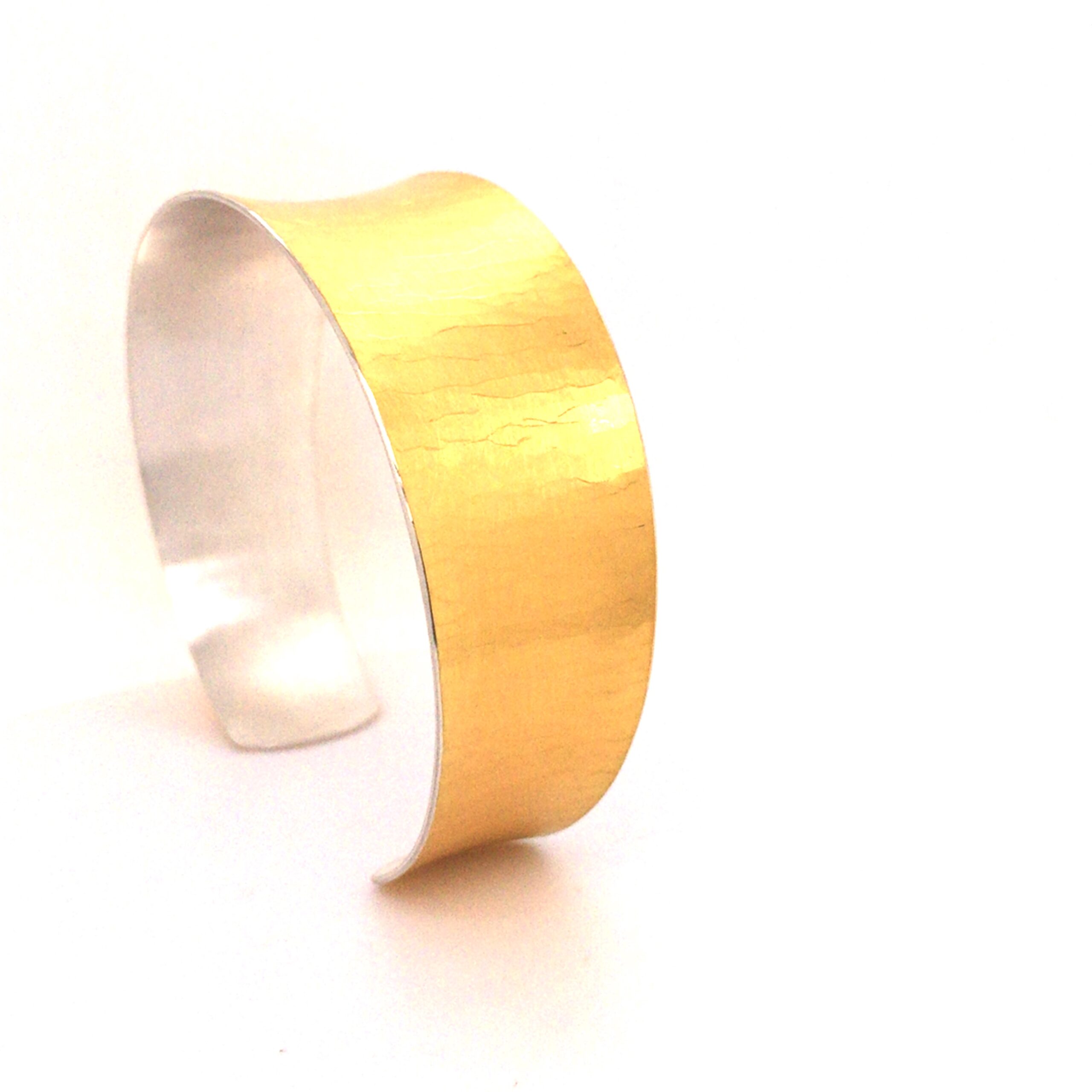 Diese Armspange ist aus Silber gefertigt und mit Feingold beschweißt. Der Hammerschlag sorgt für eine interessante Optik und der konkave Verlauf passt sich perfekt an das Handgelenk an. Tragen Sie dieses Schmuckstück alleine oder kombinieren Sie es mit anderen Armbändern für einen individuellen Look. Ein echter Hingucker für jedes Handgelenk!