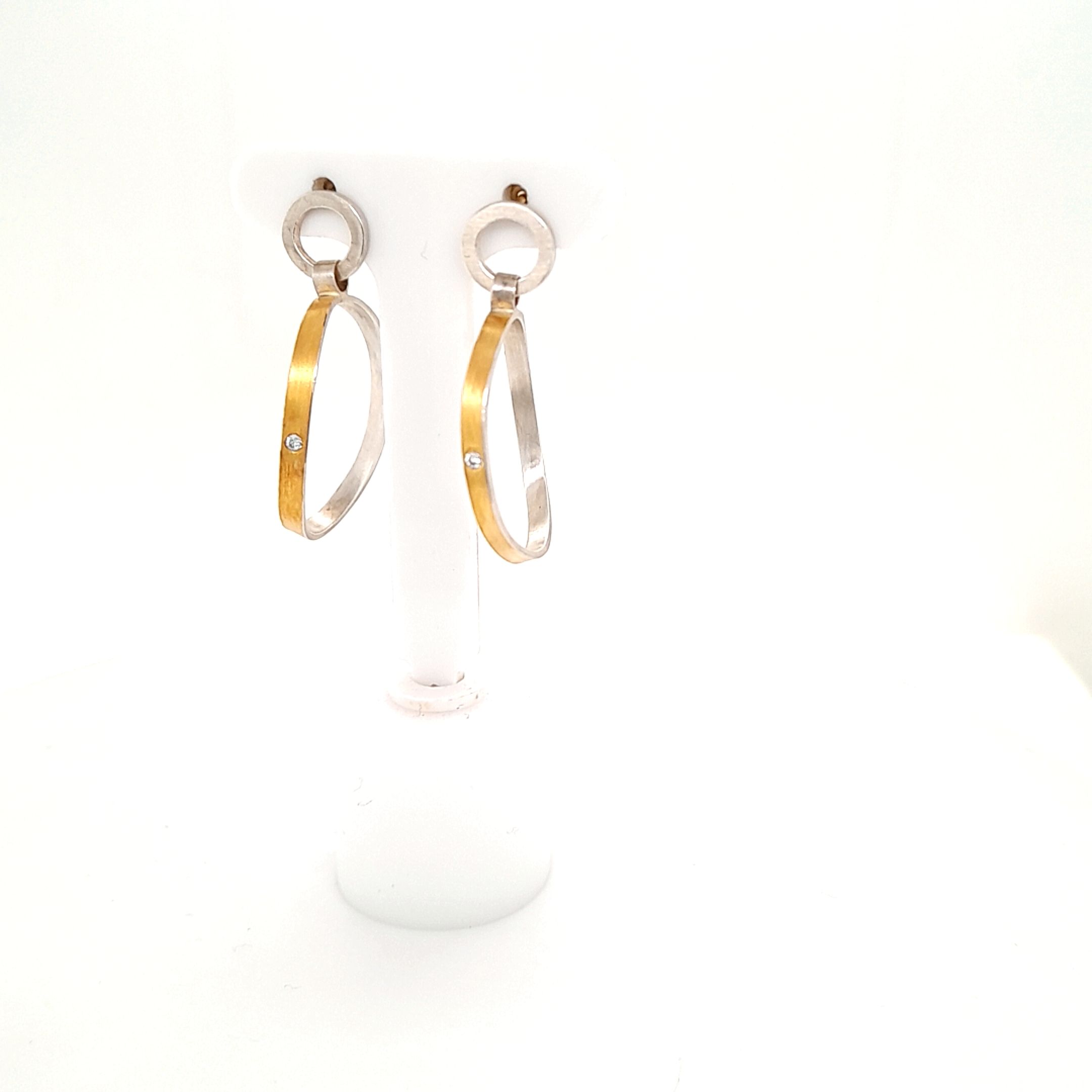 Ohrhänger Bi-Color, gefertig in Silber und Gold 900/ooo mit zwei Brillanten, zusammen 0,024ct.
Das untere Element ist beweglich. Das Obere Element ist mit einem Stecker versehen.
Durchmesser des oberen Element 0,7 cm, Maße des unteren Element 2mm Sichtfläche, 2,2 cm x 1,8 cm Breite