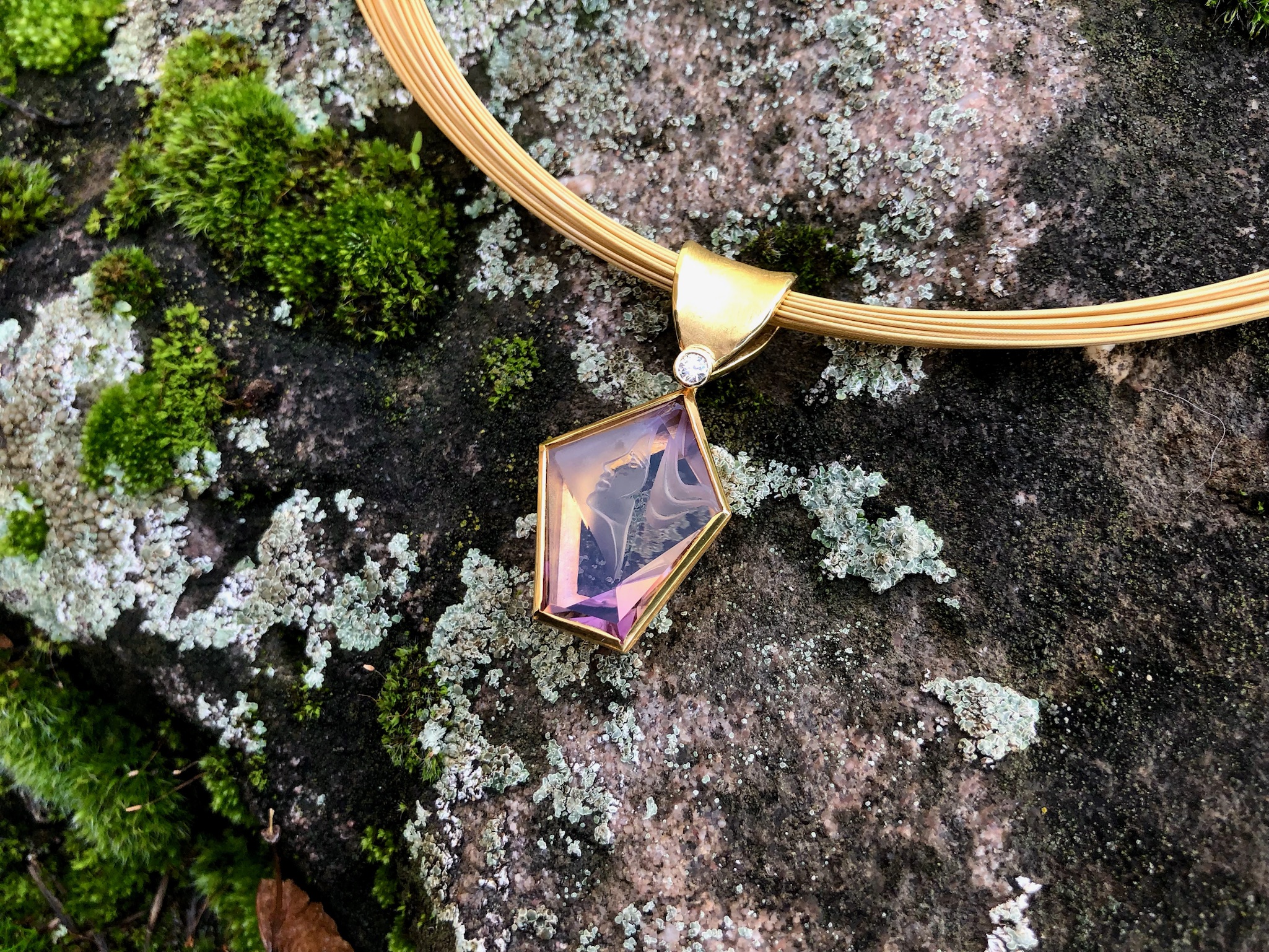 Anhänger gefertig in Gelbgold 750/ooo, mit einem gravierten Ametrin 10,91ct und einem Brillant 0,06 ct, der untere teil ist beweglich.

Länge des Anhängers 39 mm, Breite des Anhängers 19 mm

Ein Ametrin ist ein zweifarbiger Quarz, aus violttem Amethyst und gelbbraunen Citrin. Die einzigen Fundstellen von wirtschaftlicher Bedeutung liegen in Bolivien.
