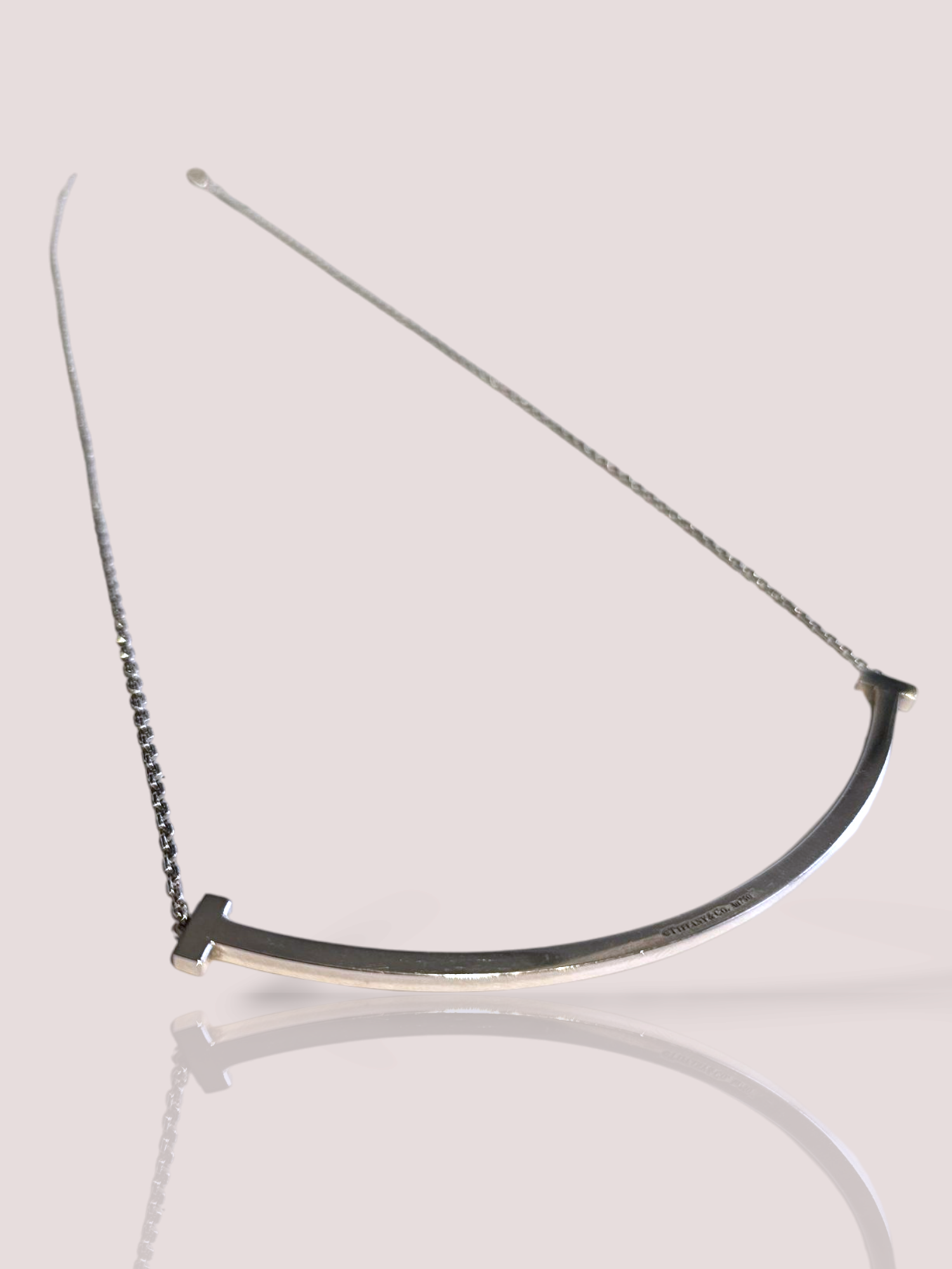 Dit vintage Tiffany & Co Smile collier is gemaakt van 18kt witgoud en straalt elegantie en stijl uit. Het collier heeft een speels design met de iconische 'Smile' van Tiffany & Co. Draag het collier alleen voor een subtiele touch of combineer het met andere sieraden voor een extra luxe uitstraling. Perfect voor elke gelegenheid!