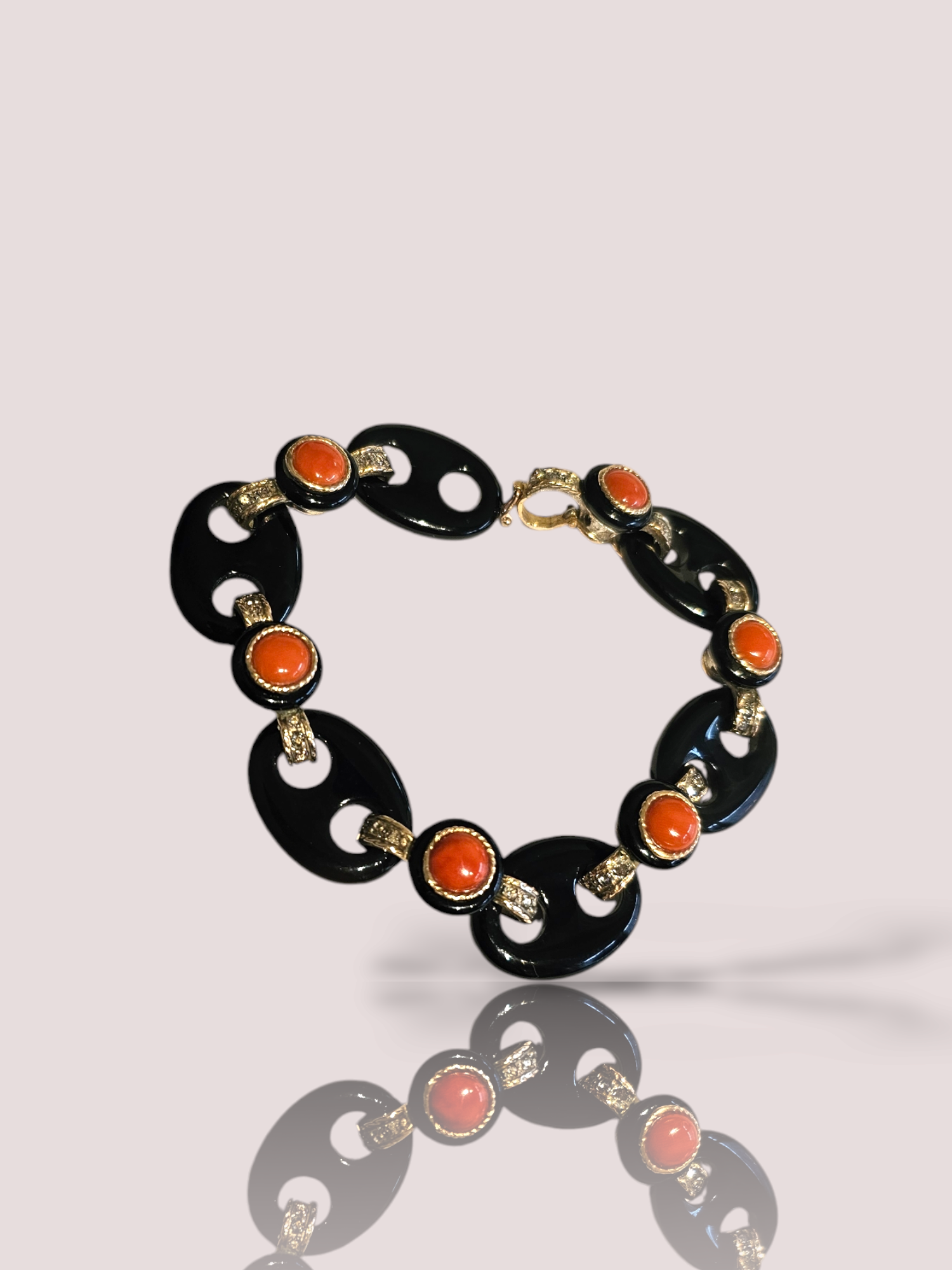 Deze prachtige vintage 14k goud en zilveren armband is versierd met stijlvolle Onyx koffieboonschakels en Bloedkoraal stenen. De armband heeft een uniek en tijdloos ontwerp dat elke outfit zal verfraaien. Draag deze armband alleen voor een subtiele en elegante look, of combineer hem met andere armbanden voor een meer gewaagde uitstraling. Een geweldige aanvulling op elke sieradencollectie! De kleur van het bloedkoraal kan in werkelijkheid afwijken van de foto.