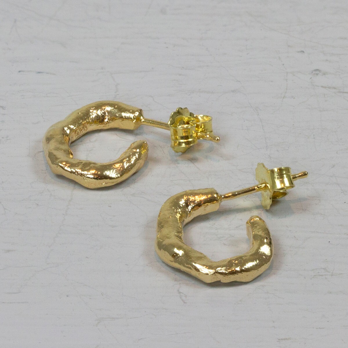 Deze Jéh Jewels oorstekers zijn gemaakt van 925 sterling zilver en zilver verguld in de vorm van een kleine organische lus.

Materiaal: 925 sterling zilver
De glans van 925 sterling zilver maakt het een gewild edelmetaal voor de vervaardiging van sieraden. Het bestaat uit 92,5% puur zilver en 7,5% koper. Puur zilver is een zacht en buigzaam materiaal, het koper in 925 sterling zilver zorgt voor de stevigheid. De sieraden van Jéh Jewels zijn nikkel vrij.

Materiaal: Zilver verguld
Vergulden is het bedekken van een voorwerp met een laagje goud. Dit artikel is door een goudbad gehaald wat ervoor zorgt dat het zilver volledig bedekt wordt met een laagje goud. Resultaat een mooie glanzende afwerking met een laagje echt goud wat ook wel silverplated of goldplated wordt genoemd.