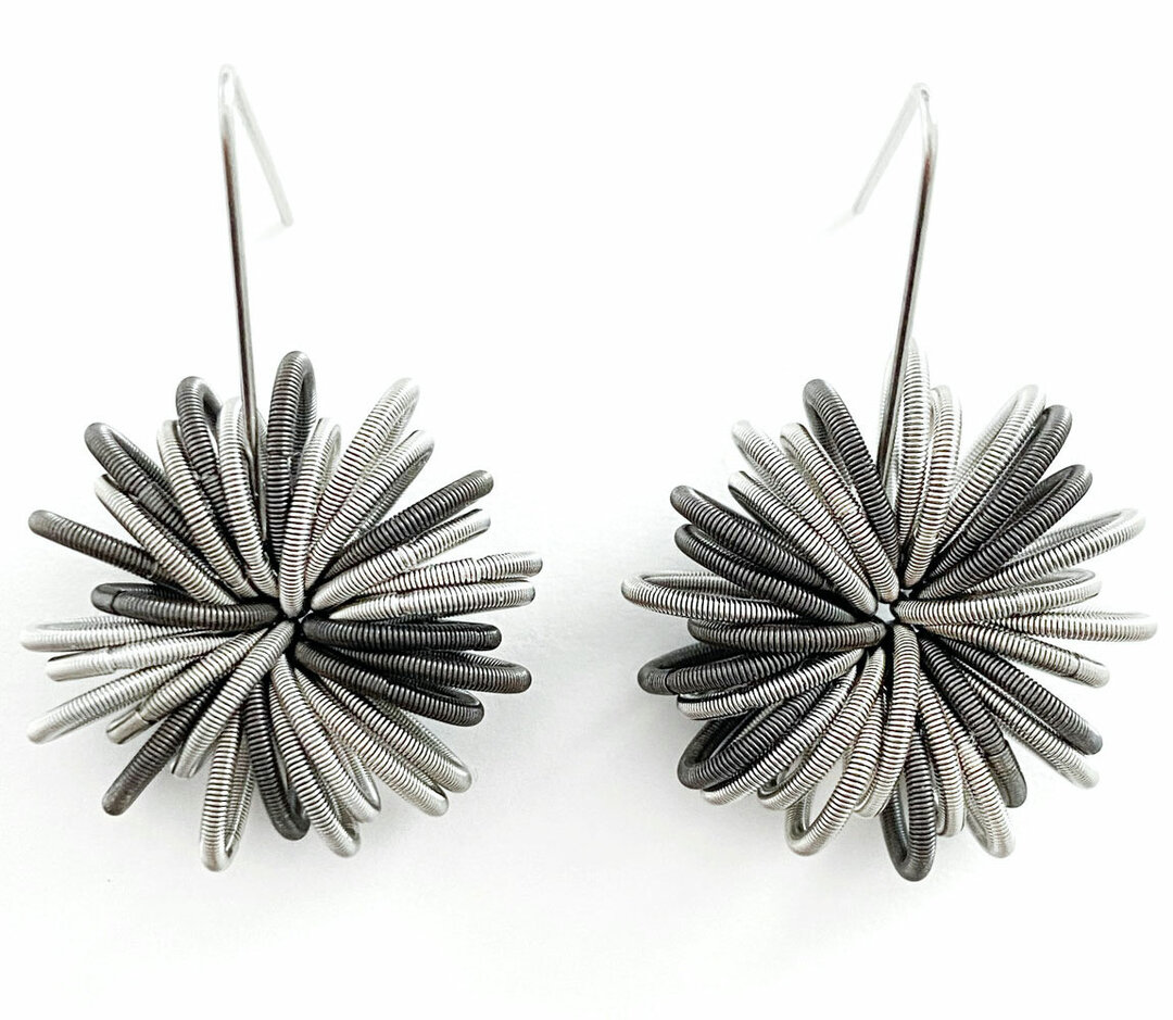 Het materiaal van de oorbellen is edelstaal en de lengte van de oorbellen is 40 mm. 
De ontwerpster van de sieraden, Tiziana Redavid, gebruikt afrikaans design als inspiratiebron. Bij deze oorbellen zijn gebruik gemaakt van zilver en donker zilver kleuren.