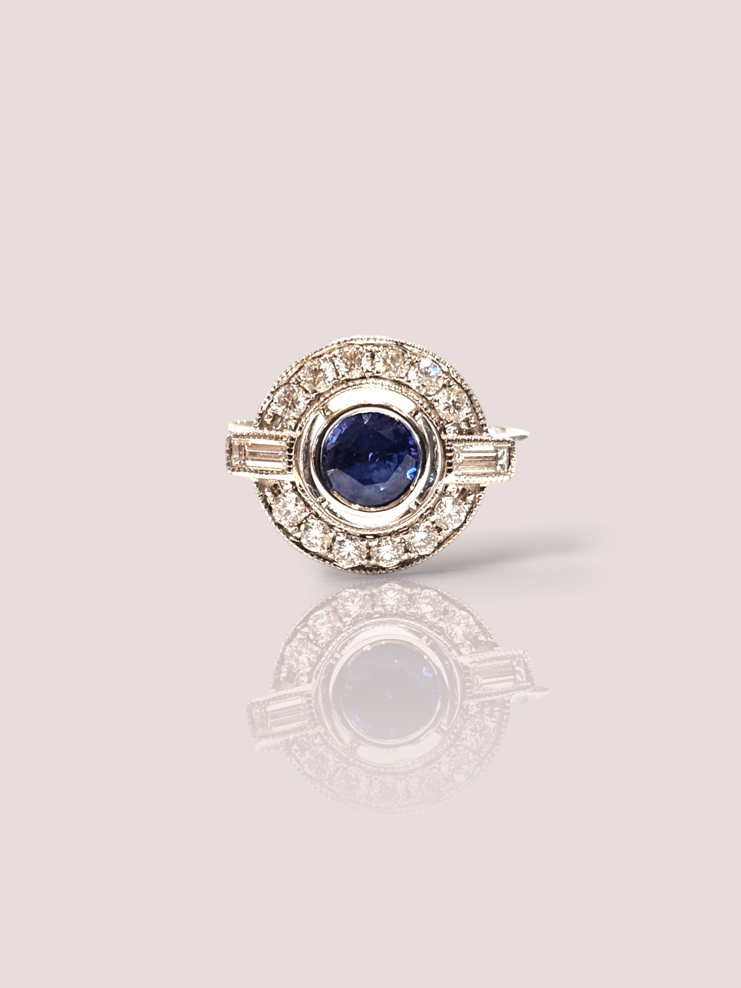 Deze prachtige vintage 18k witgouden ring is bezet met een schitterende saffier en diamanten. De ring straalt luxe en elegantie uit en is een tijdloos stuk dat perfect is voor speciale gelegenheden. Draag deze ring als een eye-catching statement piece bij een chique avondjurk of combineer hem met je dagelijkse kleding voor een vleugje glamour. De saffier heeft een diameter van 6 mm. De ring kan eventueel op maat gemaakt worden.