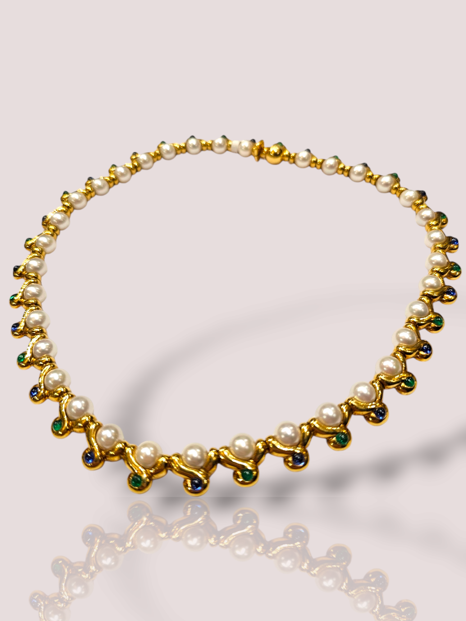 Dit vintage 18k geel gouden collier is bezet met prachtige parels en cabochon geslepen saffier en smaragd. De combinatie van deze edelstenen geeft het collier een elegante uitstraling en laat het opvallen bij elke gelegenheid. Draag dit collier met een eenvoudige jurk of blouse om de focus te leggen op dit prachtige sieraad.

Dit collier is een absoluut topstuk met een gewicht van 102 gram, 35 parels, 18 smaragden en 18 saffieren. Het collier is 42 cm lang. 