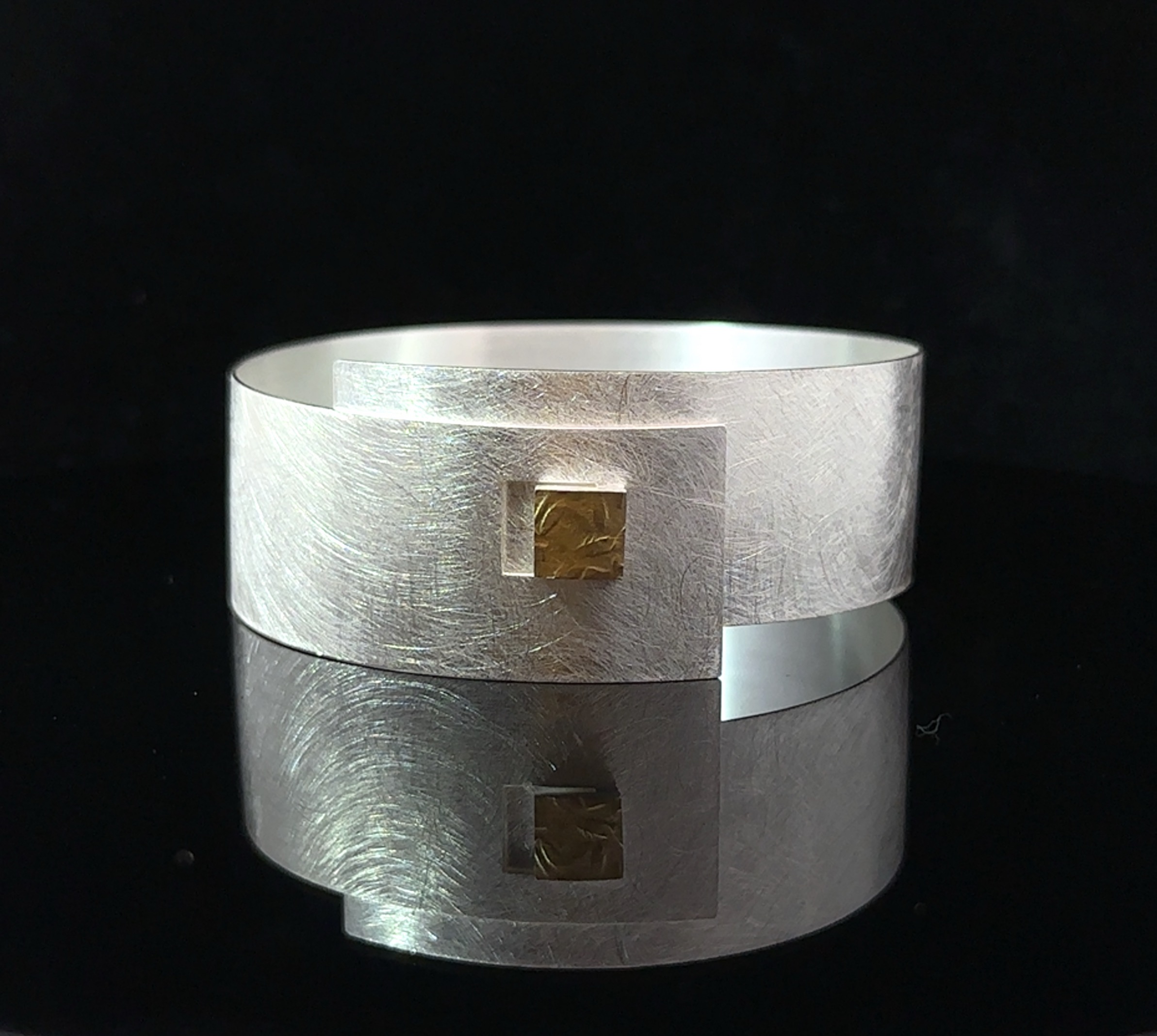 Dieser Armreif aus 925er Silber und 900er Gelbgold ist breit und im Hammerschlag-Design gefertigt. Er besticht durch seine edle Optik und hochwertige Materialien. Tragen Sie ihn alleine als Blickfang oder kombinieren Sie ihn mit anderen Schmuckstücken für einen individuellen Look. Ein zeitloses Schmuckstück für jeden Anlass!