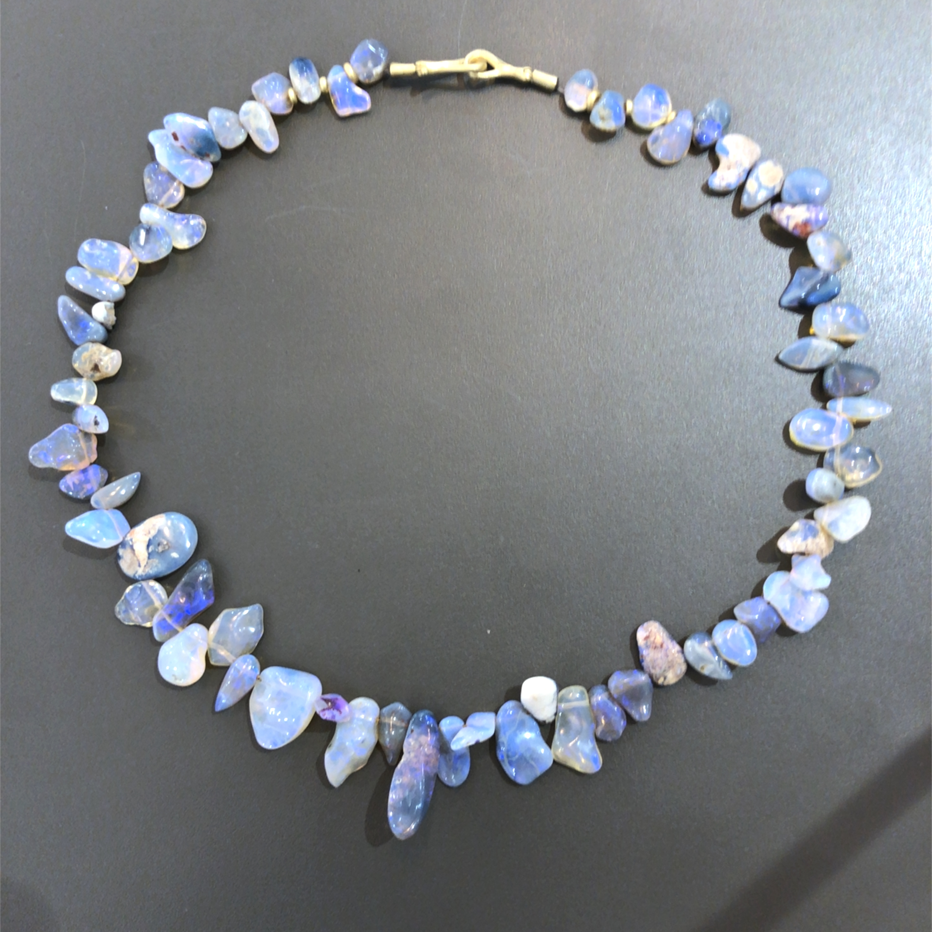 Dieses exklusive Opalcollier besteht aus Boulder Opal und 750er Gold. Ein wahres Juwel, das Eleganz und Schönheit vereint. Tragen Sie es am besten zu besonderen Anlässen über einem schlichten Kleid oder einer Bluse, um Ihrem Look das gewisse Etwas zu verleihen. Lassen Sie sich von diesem funkelnden Schmuckstück verzaubern und strahlen Sie mit der einzigartigen Schönheit des Opals.