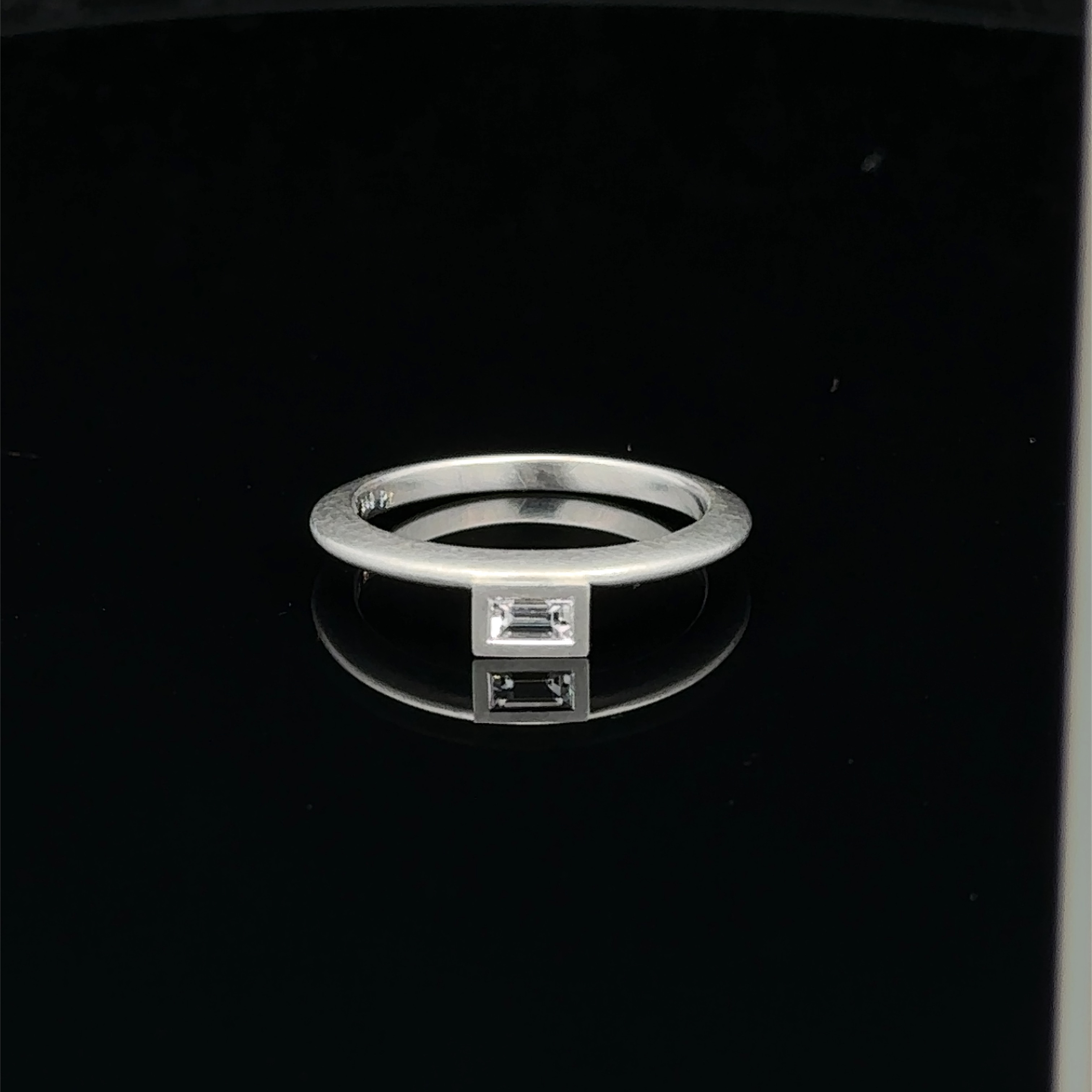 Dieser Ring mit einem Diamant im Baguette Schliff mit 0,12ct in 950/-Platin, besticht durch sein elegantes Design und den funkelnden Diamanten. Er ist explizit als Vorsteckring konzipiert, ein gleichartiger Ring in Roségold mit Brillant ist ebenfalls verfügbar. Angeboten wird nur der Platinring. Tragen Sie diesen Ring alleine für einen subtilen Look oder kombinieren Sie ihn mit anderen Schmuckstücken für ein stilvolles Ensemble. Dieser Ring ist perfekt für besondere Anlässe oder den täglichen Gebrauch und wird Ihrem Outfit einen Hauch von Luxus verleihen.