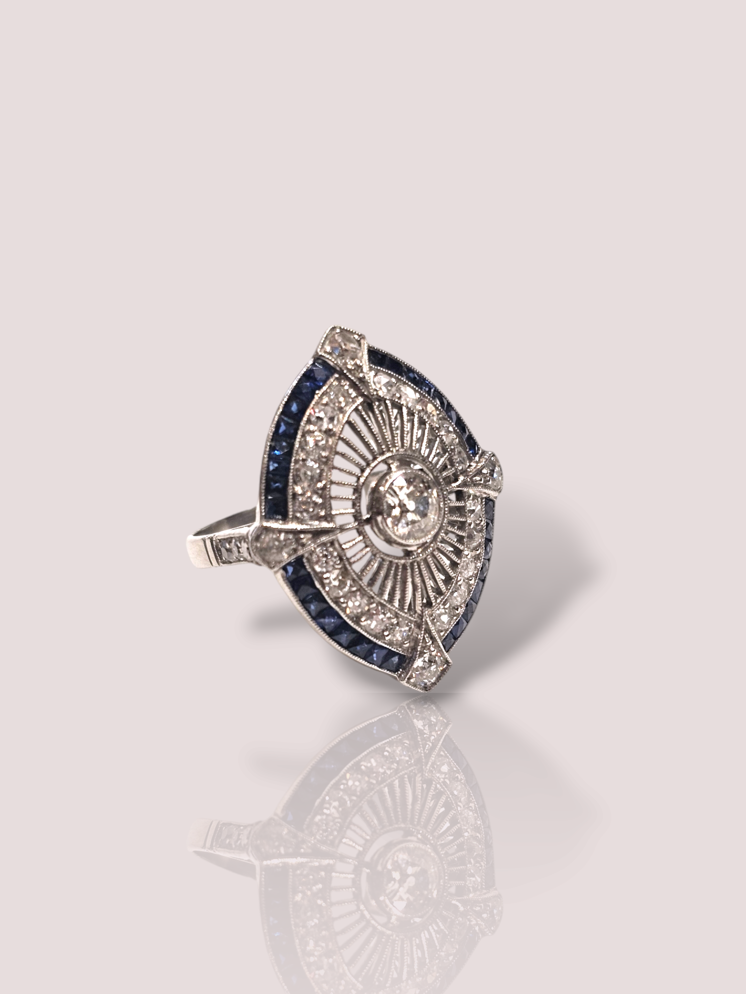 Deze vintage Art-Deco platina ring is bezet met saffieren en diamanten voor een luxe uitstraling. Draag deze ring als een statement piece om je outfit compleet te maken. De combinatie van de blauwe saffieren en sprankelende diamanten maakt het een uniek en tijdloos stuk. Perfect voor speciale gelegenheden of als een elegante toevoeging aan dagelijkse looks. Maak een statement met deze prachtige ring!

De ring is 2,8 mm hoog en 2,1 mm breed en bevat 32 princess geslepen saffieren en 24 old cut geslepen diamanten. De center stone is een prachtige Bolsjewiek geslepen 0,40ct diamant.
