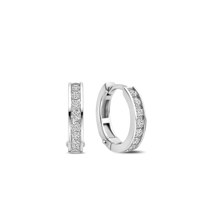 Hul jezelf met moderne elegantie met de TI SENTO Pave Silver Hoop Earrings 7973ZI. Gemaakt van 925 sterling zilver en verguld met platina voor blijvende schittering, hebben deze oorbellen twee kleine hoepels versierd met een verblindende rij rechthoekig geslepen witte cubic zirconia stenen. De geometrische vorm van de stenen voegt een vleugje gedurfde verfijning toe aan het klassieke hoepelontwerp. Dit paar oorbellen is een bewijs van de kunst van fijne sieraden, met een harmonieuze mix van traditie en moderniteit. Het koele zilver en de sprankelende cubic zirconia stenen creëren een betoverend spel van licht en textuur. Verhoog je dagelijkse look met deze delicate minimalistische stukken. Draag ze alleen voor een minimalistische uitspraak of gecombineerd met andere TI SENTO oorbellen voor een gepersonaliseerde touch die vertrouwen en aantrekkingskracht uitstraalt. Laat deze oorbellen de vonk zijn die je innerlijke uitstraling ontsteekt. Met zorg vervaardigd voor gevoelige huid, zorgen deze nikkelvrije en hypoallergene oorbellen voor langdurig comfort en kwaliteit.