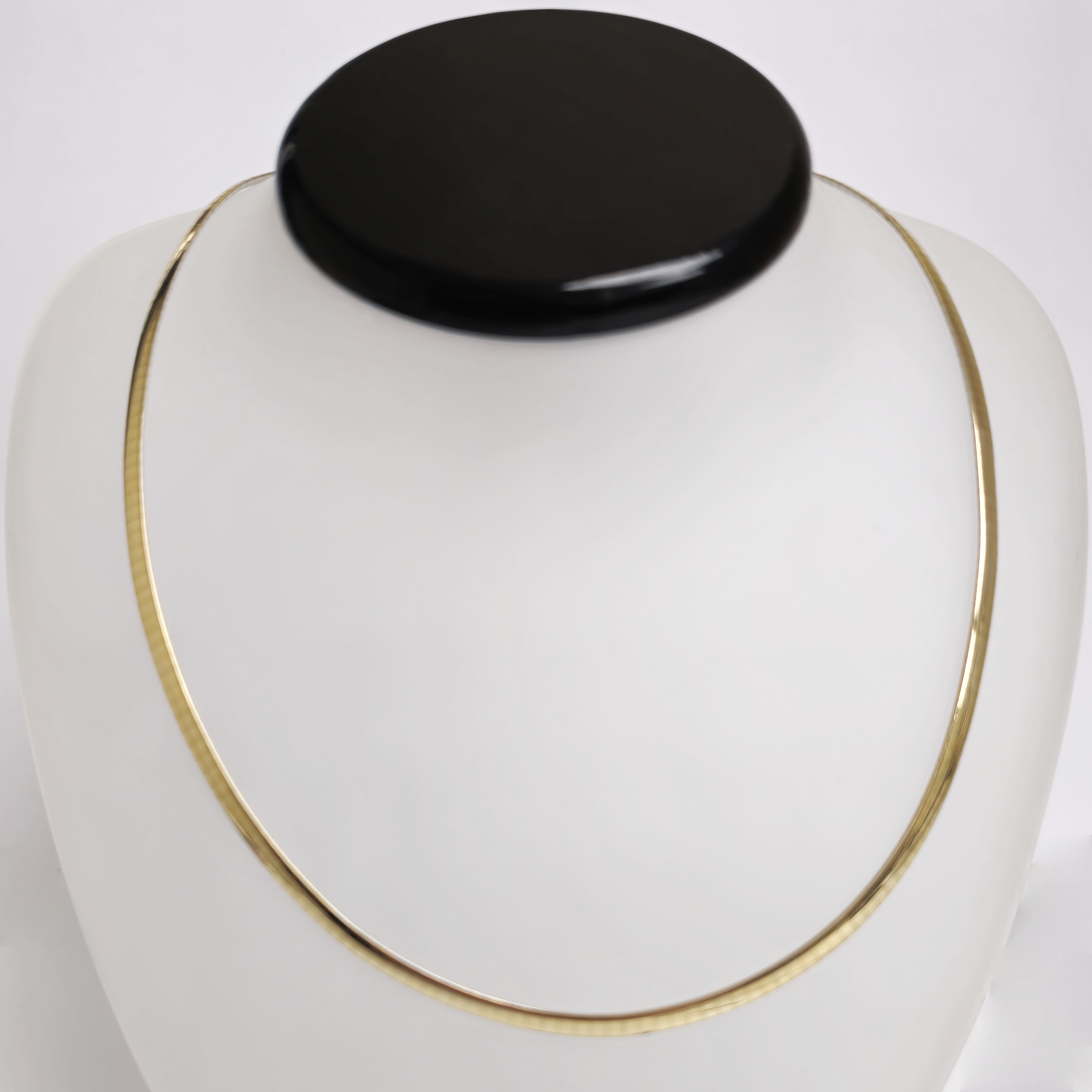 Arn van Ess Omega collier vlak 3 mm breed 40 cm lang tweezijdig te dragen . 
1 zijde geel goud 1 zijde witgoud 