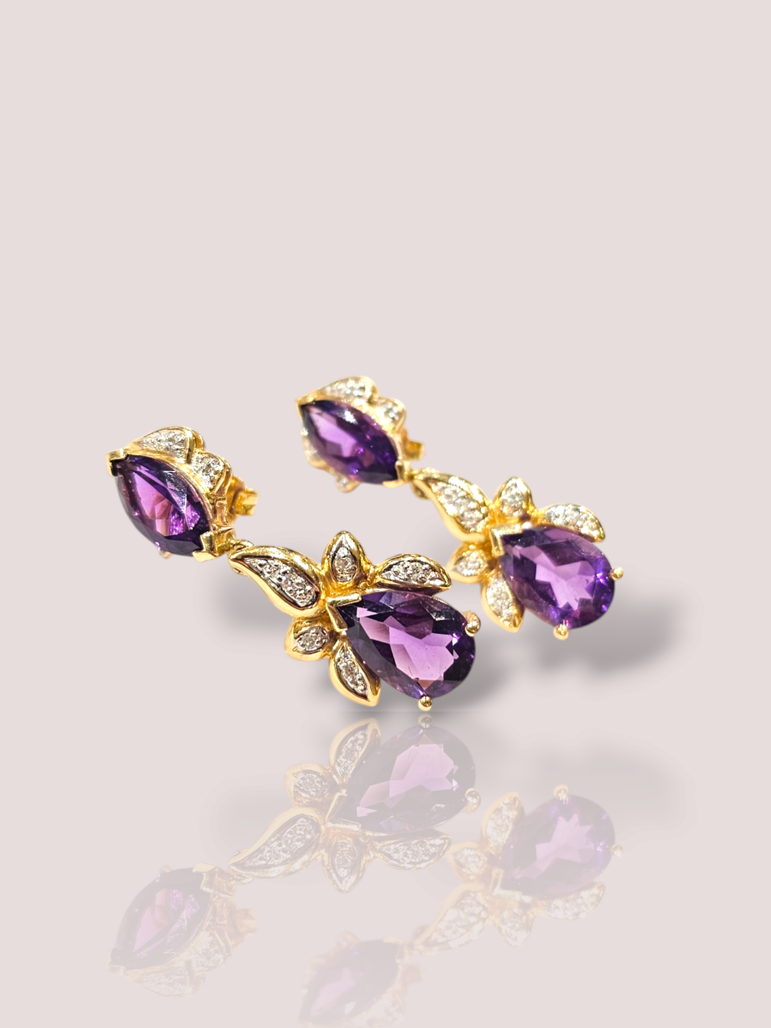 Deze vintage 14k geel gouden oorbellen met amethist en diamant stralen pure elegantie uit. De combinatie van de dieppaarse amethiststenen en de sprankelende diamanten zorgt voor een tijdloze en luxe uitstraling. Draag deze oorbellen met een elegant avondjurkje voor een chique uitstraling of met een casual outfit voor een vleugje glamour. Voeg deze prachtige oorbellen toe aan je collectie voor een onvergetelijke look.

De oorbellen zijn 3,5 cm lang en bevatten 1 marquise geslepen en 1 peer geslepen amethist en 9 briljant geslepen diamanten.
