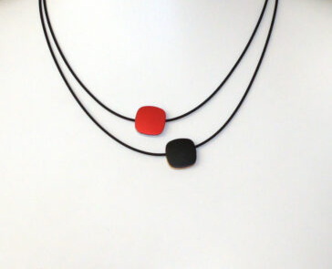 Rubber met collier met aluminium elementen en rood en zwart , de andere kant van de elementen zijn goud en zilverkleurig. Dus aan 2 kanten te dragen. 