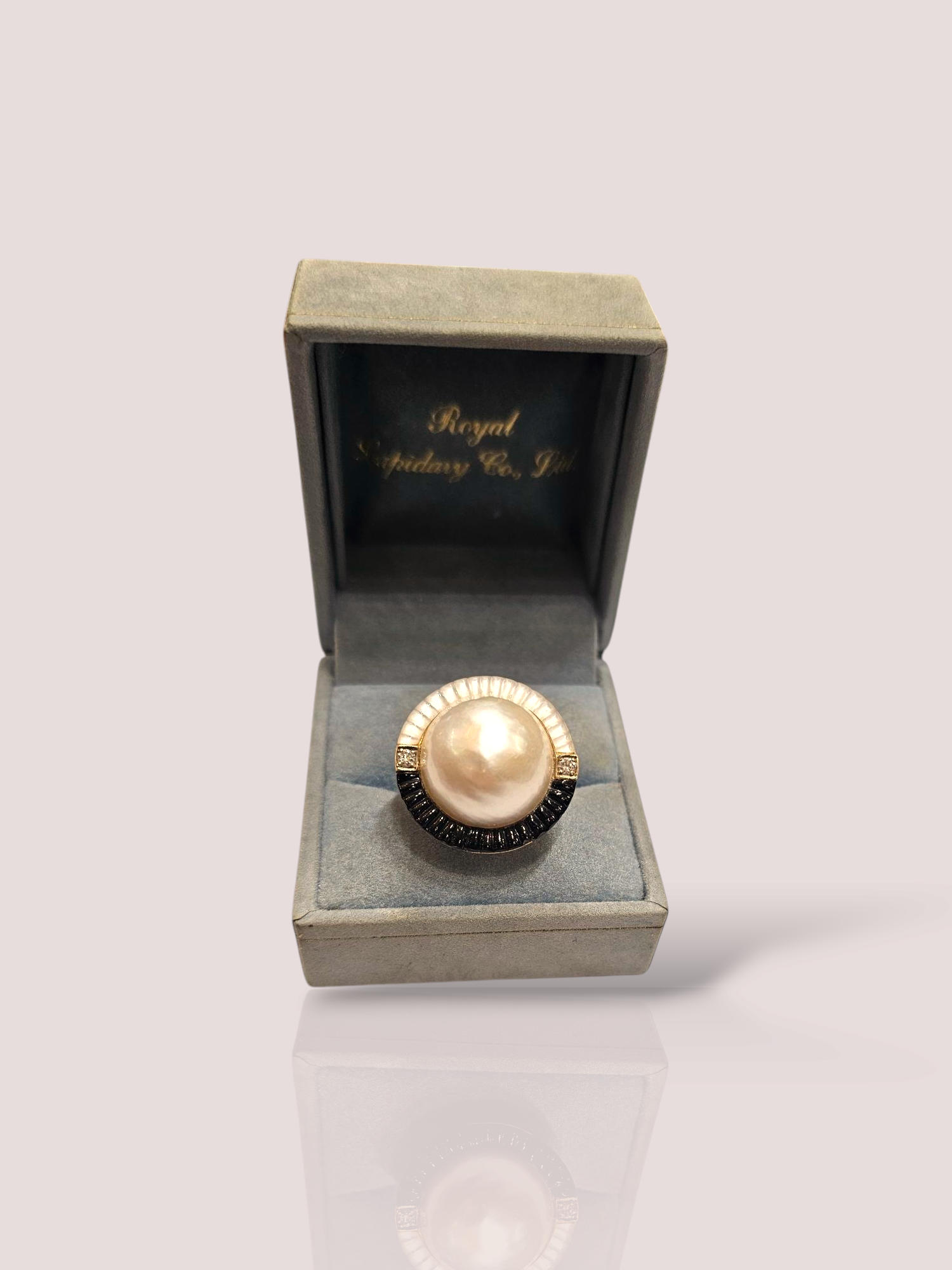 Dit unieke juweel is een vintage 18k geel gouden 'Pierot' ring met een prachtige mabe parel, parelmoer en onyx. De ring heeft ook twee diamantjes van 0,03ct. Deze cultivé parel heeft een diameter van 1,8 cm. De ring straalt elegantie uit en past perfect bij zowel chique gelegenheden als bij dagelijkse outfits. Combineer het met andere gouden sieraden voor een schitterende uitstraling of draag het als een opvallend statement stuk. De mogelijkheden zijn eindeloos!

De ring kan desgewenst op maat gemaakt worden. 