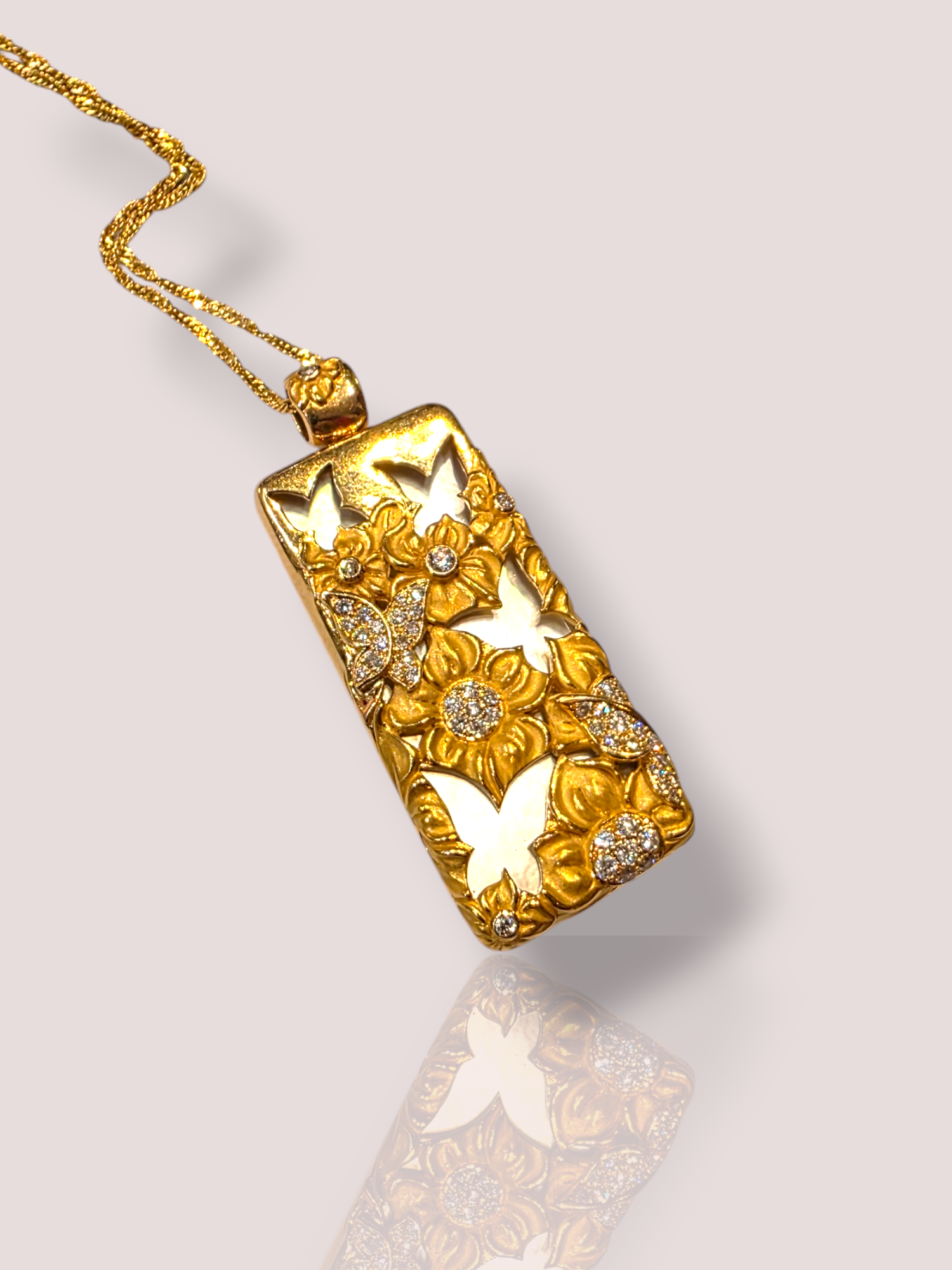 Dit prachtige Vintage 18k geelgouden collier combineert elegantie met verfijning. Het collier heeft een gouden hanger met daarin parelmoer gelegd. Op de hanger zijn in goud bloemen en vlinders gemaakt met sprankelende diamanten, wat het collier tot een heel bijzonder juweel maakt. 

Perfect te combineren met een chique avondjurk of als statement-stuk bij een eenvoudige outfit. Draag het met trots om je hals en straal tijdloze allure uit. 