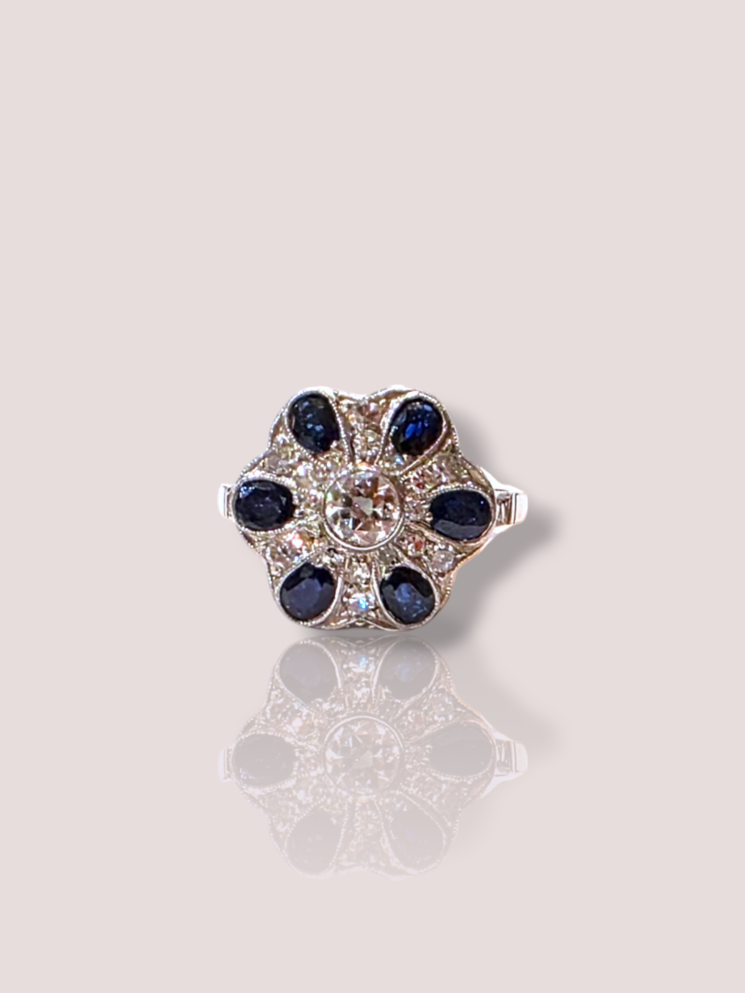 Deze vintage platina art-deco ring combineert elegantie met luxe, met schitterende saffieren en diamanten. Dit juweel is de perfecte keuze voor speciale gelegenheden. Draag de ring als een opvallend accessoire op een feestelijke outfit of als dagelijks teken van verfijndheid. Laat je hand stralen met deze prachtige platina creatie!

De ring bevat 6 ovaal geslepen natuurlijke saffieren en heeft een prachtige Bolsjewiek geslepen 0,35ct diamant in het midden. Rondom de saffieren zijn nog eens 18 diamanten gezet, evenals op de pootjes van de ring aan weerszijden.