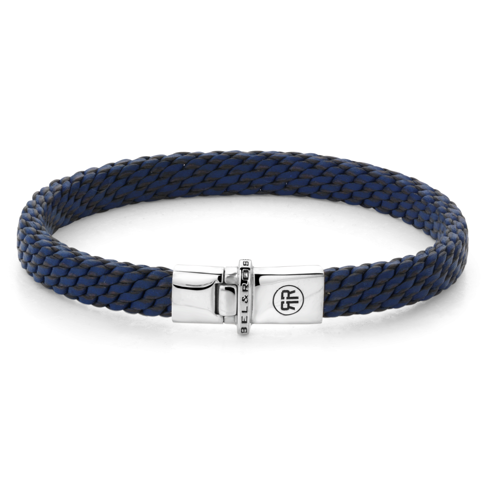 De Mastery Collection - Woven Small Blue is 7 mm breed en de sluiting is gemaakt van 925 Sterling Silver. Deze armband maakt deel uit van de Mastery Collection: dit zijn handgemaakte, exclusieve sieraden, die op een unieke en zeer arbeidsintensieve manier zijn gemaakt. De Mastery Collection van Rebel & Rose is een bijzondere serie handgemaakte armbanden van 8 gevlochten strengen van 1,5 mm breed. De kern van het vlechtwerk bestaat uit één leren koord. Het maken van deze armbanden is complex en zeer arbeidsintensief. Een geoefende vlechter kan er drie per dag maken. Na het vlechten worden de banden in water behandeld, geperst, gedroogd, weer nat gemaakt, gerold, geperst en vervolgens gewaxt en weer gedroogd. In totaal duurt de afwerking nog 3 dagen. Behalve in het regenseizoen, dan duurt het langer, want het leer moet buiten drogen. Het resultaat mag er echter zijn: een bijzonder exclusieve armband, die heel comfortabel en soepel is om te dragen.