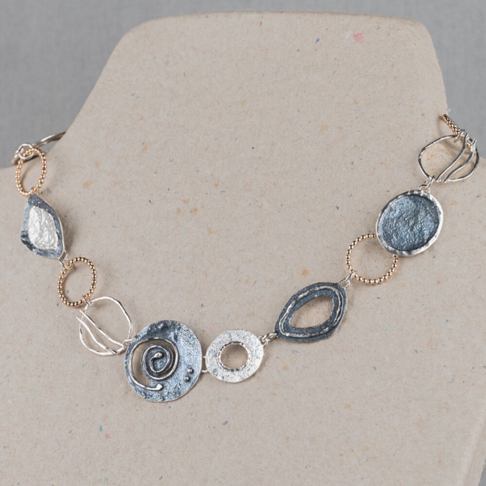 Collier uit de Touch of Gold-collectie van Jeh Jewels, gemaakt van 925 sterling zilver met hoogglans, geoxideerd zilver en een laagje Goldfilled. Dit collier bestaat uit verschillende organische vormen, wisselend van materiaal. Dit collier doet ons denken aan een dagje relaxen op het strand, stylish en bohemian!