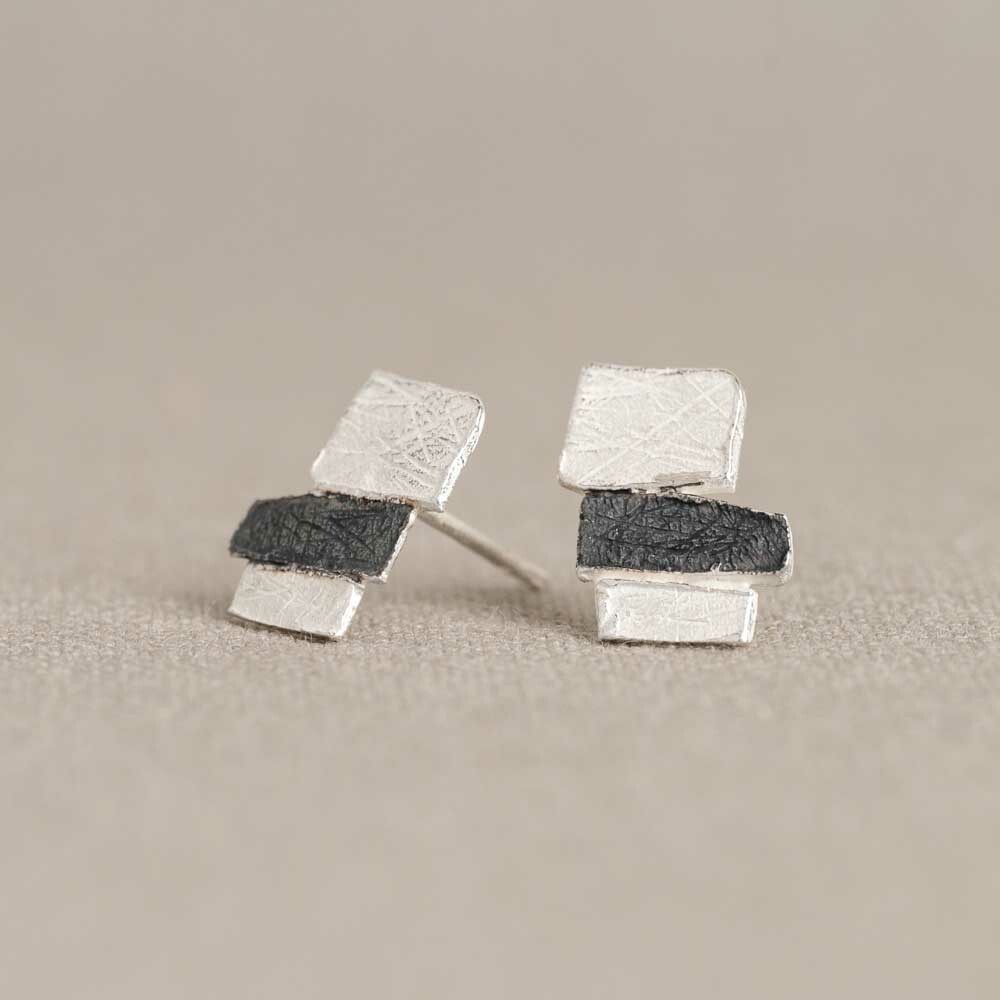 Deze oorhangers zijn gemaakt van 925 sterling zilver en bestaan uit drie opgestapelde rechthoekjes met een ambachtelijke structuur.