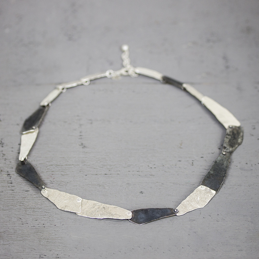 Collier gemaakt van 925 sterling zilver, bestaande uit grove schakels. Deze schakels hebben verschillende afmetingen en zijn bewerkt met een lichte hamerslag.