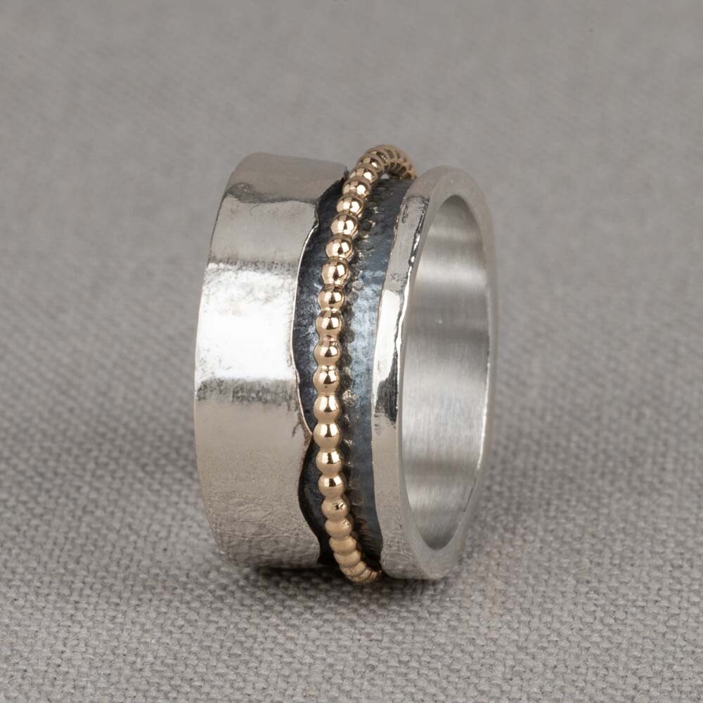 Bijzondere ring gemaakt van (geoxideerd) 925 sterling zilver en gold filled. De ring in het midden van de ring kan bewegen, dit zorgt voor een speels effect. Onder de ring is gebruik gemaakt van geoxideerd zilver. Doordat de ring speels beweegt, is het mogelijk dat de geoxideerde laag na verloop van tijd vervaagd. De glans van 925 sterling zilver maakt het een gewild edelmetaal voor de vervaardiging van sieraden. Het bestaat uit 92,5% puur zilver en 7,5% koper. Puur zilver is een zacht en buigzaam materiaal, het koper in 925 sterling zilver zorgt voor de stevigheid. De sieraden van Jeh Jewels zijn nikkel vrij. Gold filled komt uit Amerika en wordt daar al langer gebruikt voor de vervaardiging van sieraden met een "touch of gold" voor een betaalbare prijs. Het gold filled blijft op kleur, is slijtvast en de 14karaats goudlaag is dik genoeg om lang te kunnen genieten van de warme uitstraling van goud. Gold filled wordt veelal ook goed verdragen door mensen die allergisch zijn voor andere metalen dan goud.