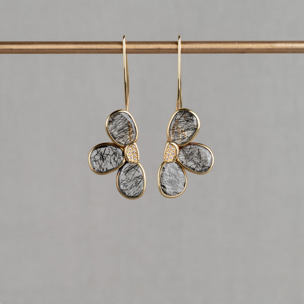 Oorhangers gemaakr van 14 karaat goud met beide een halve bloem gemaakt van de edelsteen Black Rutielkwarts, die samen een hele bloem vormen. In het midden van de bloem zitten diamanten. Combineer met de andere gouden sieraden uit de Rocky-lijn.