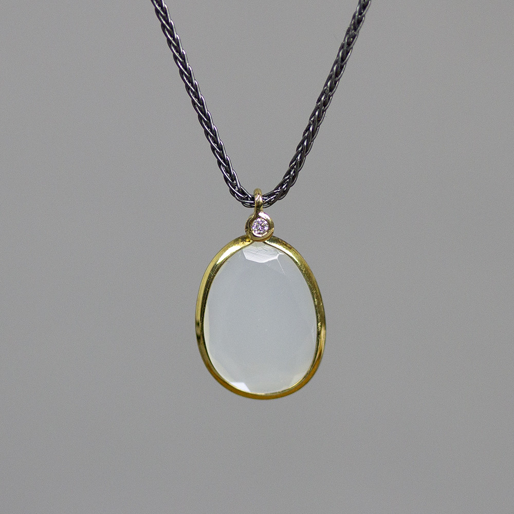 Collier zilver + G14K met Maansteen en een diamant 0.01CT H/SI. De gouden sieradenlijn van Jeh is gemaakt van 14 karaats goud. Dit karaatgehalte wordt in Nederland het meest gebruikt, vanwege de hardheid en de kleur. Puur goud is te zacht om draagbare sieraden van te maken, daarom worden er bij metalen gebruikt. Vaak wordt er zilver en koper gebruikt zodat je kunt blijven spreken van &lsquo;edele metalen&rsquo;. Bij 14 karaat goud zijn er van de 1000 delen, 585 delen puur goud. De overige 415 delen bestaan dus uit de overige metalen.