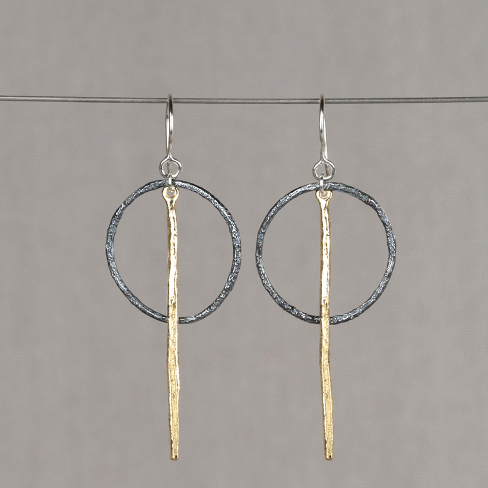 Oorhanger gemaakt van 925 sterling zilver, geoxideerd zilver en G14K zilver verguld. Aan de oorhanger hangt een geoixideerde cirkel, voor de cirkel hangt de vergulde pin.