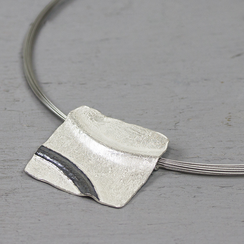 Hanger gemaakt van 925 sterling zilver met geoxideerd zilver. De vierkante hanger heeft aan de achterkant een speciale buis waar de spang doorheen gaat. De glans van 925 sterling zilver maakt het een gewild edelmetaal voor de vervaardiging van sieraden. Het bestaat uit 92,5% puur zilver en 7,5% koper. Puur zilver is een zacht en buigzaam materiaal, het koper in 925 sterling zilver zorgt voor de stevigheid. De sieraden van Jeh Jewels zijn nikkel vrij.