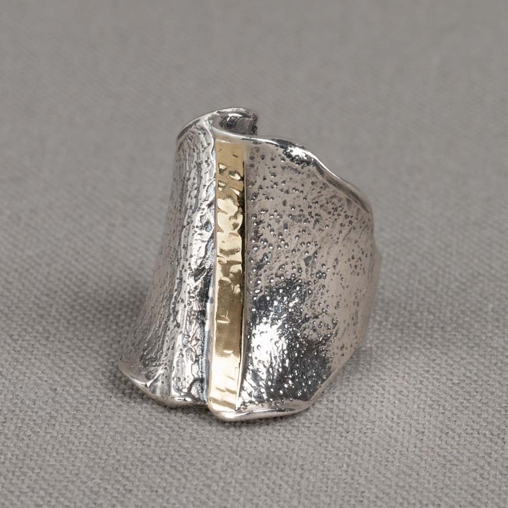Ring gemaakt van 925 sterling zilver en geoxideerd zilver. De ring is aan de voorkant breder dan aan de achterkant. Aan de voorkant zit een verticale bang van 9 karaat..

Materiaal: 925 sterling zilver
De glans van 925 sterling zilver maakt het een gewild edelmetaal voor de vervaardiging van sieraden. Het bestaat uit 92,5% puur zilver en 7,5% koper. Puur zilver is een zacht en buigzaam materiaal, het koper in 925 sterling zilver zorgt voor de stevigheid. De sieraden van Jéh Jewels zijn nikkel vrij.

Materiaal: 9 karaat
De term karaat geeft aan hoeveel puur goud er per duizend delen in een sieraad zitten. Hoe hoger deze waarde, hoe meer goud. In een sieraad van 9 karaat zitten 337,5 delen goud.