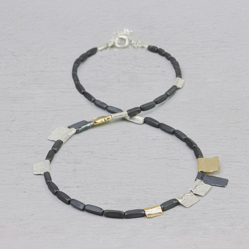 Collier gemaakt van 925 sterling zilver, geoxideerd zilver en zilver verguld. Tussen deze drie kleuren zitten stenen van Hematiet. Hematiet vergroot het zelfrespect, verbetert de concentratie en stimuleert de opname van ijzer in de bloedsomloop.