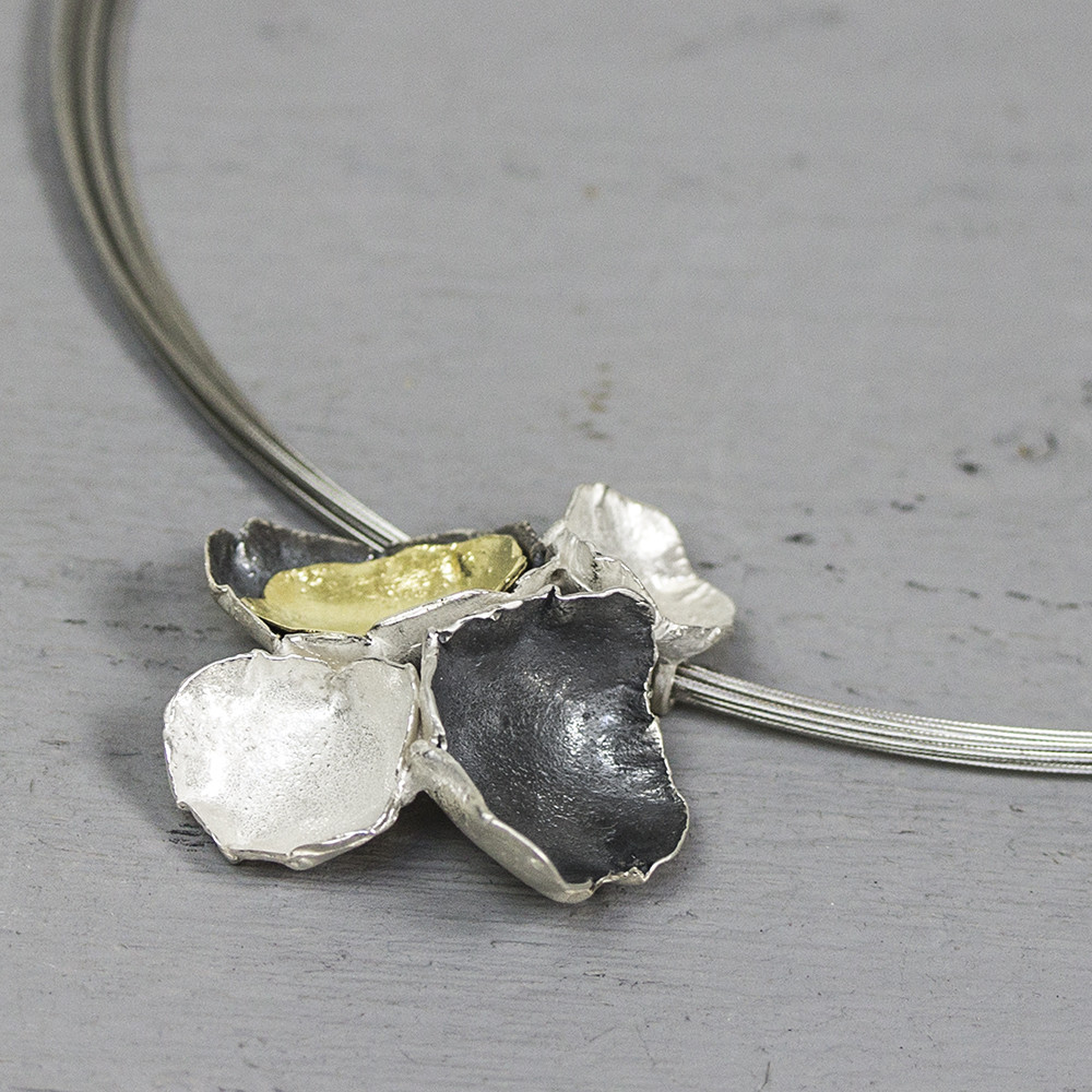 Hanger gemaakt van 925 sterling zilver, geoxideerd zilver en zilver verguld. Deze hanger bestaat uit verschillende organische elementen die samen een bloem vormen.