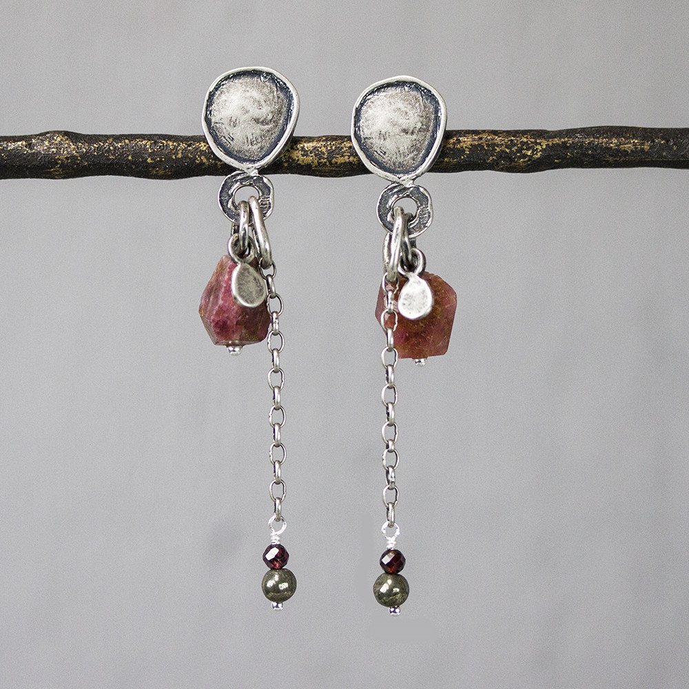 Oorsteker gemaakt van 925 sterling geoxideerd zilver met daaraan verschillende edelstenen. Van boven naar beneden is dat: roze Tourmalijnkwarts, Granaat en Pyriet.