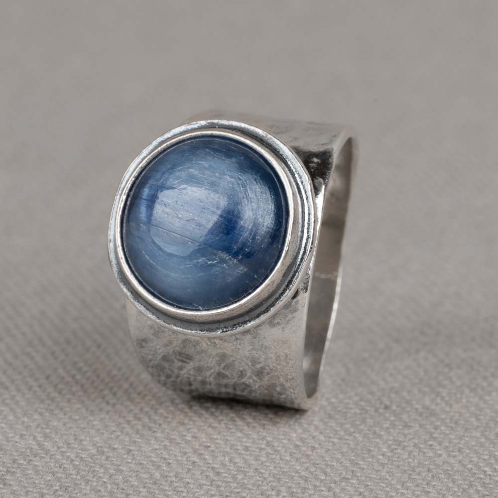 Ring gemaakt van 925 geoxideerd sterling zilver, met een edelsteen cabochon geslepen van Kyaniet. Kyaniet is een spirituele steen met een kalmerende en evenwichtige werking. Het helpt ons de regie over ons eigen leven voeren en om in te zien dat we geen marionetten van het lot zijn maar onze eigen toekomst vorm kunnen geven.