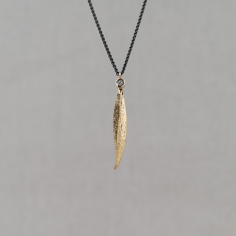 Collier gemaakt van 925 geoxideerd sterling zilver met daaraan een bladvormige hanger van 14 karaat goud. In het blad bovenin zit een diamant van 0.01 ct.
