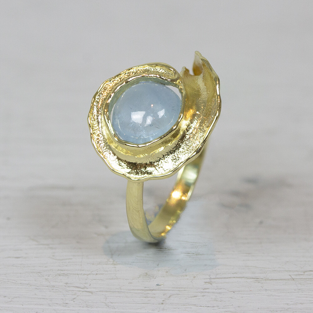 Ring van Jeh Jewels gemaakt van 14 karaat goud, met in de krulvormige ring een Milky Aquamarijn. Bij Jéh Jewels werken wij met echte edelstenen, dit zijn natuurlijke producten waardoor niet iedere steen hetzelfde is. Ieder sieraad is hierbij dus uniek. De kleur en structuur van de steen kan afwijken van de foto op de website. De gouden sieradenlijn van Jéh is gemaakt van 14 karaats goud. Dit karaatgehalte wordt in Nederland het meest gebruikt, vanwege de hardheid en de kleur. Puur goud is te zacht om draagbare sieraden van te maken, daarom worden er bij metalen gebruikt. Vaak wordt er zilver en koper gebruikt zodat je kunt blijven spreken van 'edele metalen'. Bij 14 karaat goud zijn er van de 1000 delen, 585 delen puur goud. De overige 415 delen bestaan dus uit de overige metalen.