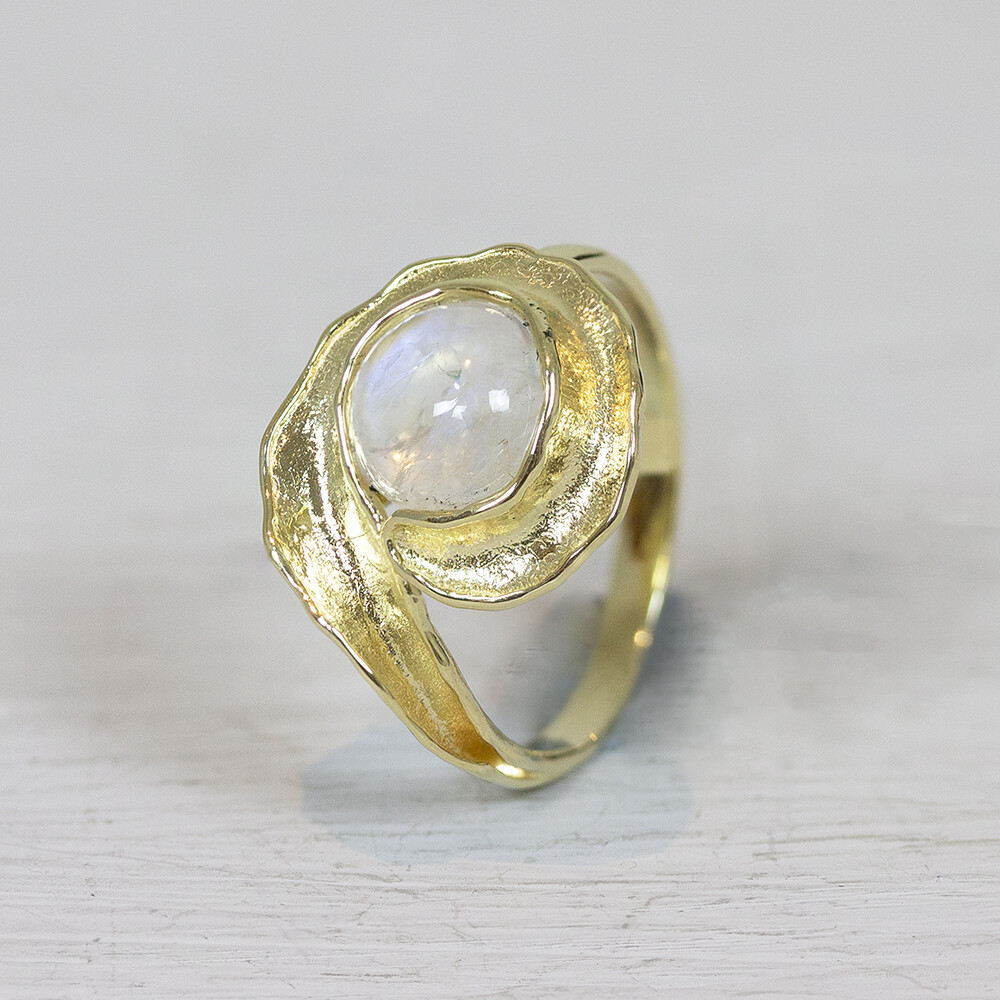 Ring van Jeh Jewels gemaakt van 14 karaat goud, in de krulvormige ring zit een regenboog maansteen. Bij Jéh Jewels werken wij met echte edelstenen, dit zijn natuurlijke producten waardoor niet iedere steen hetzelfde is. Ieder sieraad is hierbij dus uniek. De kleur en structuur van de steen kan afwijken van de foto op de website. De gouden sieradenlijn van Jéh is gemaakt van 14 karaats goud. Dit karaatgehalte wordt in Nederland het meest gebruikt, vanwege de hardheid en de kleur. Puur goud is te zacht om draagbare sieraden van te maken, daarom worden er bij metalen gebruikt. Vaak wordt er zilver en koper gebruikt zodat je kunt blijven spreken van 'edele metalen'. Bij 14 karaat goud zijn er van de 1000 delen, 585 delen puur goud. De overige 415 delen bestaan dus uit de overige metalen.