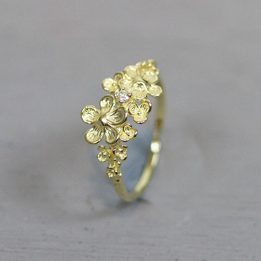 Bloesem ring van Jeh Jewels gemaakt van 14 karaat goud, in de ring zit een diamant. De gouden sieradenlijn van Jéh is gemaakt van 14 karaats goud. Dit karaatgehalte wordt in Nederland het meest gebruikt, vanwege de hardheid en de kleur. Puur goud is te zacht om draagbare sieraden van te maken, daarom worden er bij metalen gebruikt. Vaak wordt er zilver en koper gebruikt zodat je kunt blijven spreken van 'edele metalen'. Bij 14 karaat goud zijn er van de 1000 delen, 585 delen puur goud. De overige 415 delen bestaan dus uit de overige metalen.