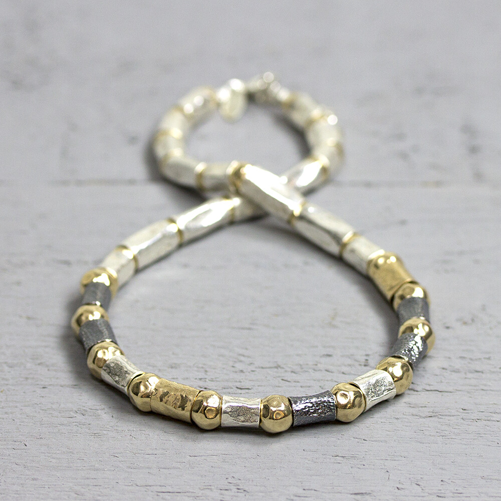 Collier gemaakt van 925 sterling zilver, geoxideerd zilver en goldfilled. Het collier bestaat uit verschillende grootte buisjes en hamerslag balletjes. Het collier is erg soepel waardoor hij mooi valt in de hals. 

Materiaal: Zilver
De glans van 925 sterling zilver maakt het een gewild edelmetaal voor de vervaardiging van sieraden. Het bestaat uit 92,5% puur zilver en 7,5% koper. Puur zilver is een zacht en buigzaam materiaal, het koper in 925 sterling zilver zorgt voor de stevigheid. De sieraden van Jéh Jewels zijn nikkel vrij.

Materiaal: Geoxideerd zilver
Op dit sieraad is gebruik gemaakt van geoxideerd zilver, dit is een oppervlakte bewerking. Het is mogelijk dat de geoxideerde laag na verloop van tijd door slijtage gaat vervagen.

Materiaal: Gold filled
Gold filled komt uit Amerika en wordt daar al langer gebruikt voor de vervaardiging van sieraden met een "touch of gold" voor een betaalbare prijs. Het gold filled blijft op kleur, is slijtvast en de goudlaag is dik genoeg om lang te kunnen genieten van de warme uitstraling van goud. Gold filled wordt veelal ook goed verdragen door mensen die allergisch zijn voor andere metalen dan goud.