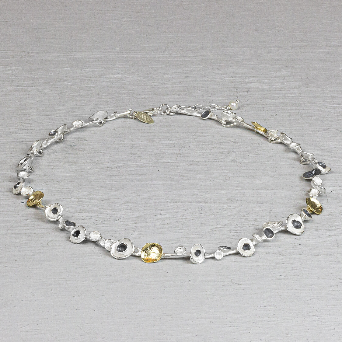 Collier van de najaarscollectie 2022 van Jeh Jewels met 3 kleuren snoepjes. Dit collier is gemaakt drie verschillende materialen. Namelijk geoxideerd zilver, verguld zilver en zilver. De vorm heeft iets weg van snoepjes, vandaar de naam. De glans van 925 sterling zilver maakt het een gewild edelmetaal voor de vervaardiging van sieraden. Het bestaat uit 92,5% puur zilver en 7,5% koper. Puur zilver is een zacht en buigzaam materiaal, het koper in 925 sterling zilver zorgt voor de stevigheid. De sieraden van Jéh Jewels zijn nikkel vrij. Op dit sieraad is gebruik gemaakt van geoxideerd zilver, dit is een oppervlakte bewerking. Het is mogelijk dat de geoxideerde laag na verloop van tijd door slijtage gaat vervagen. Vergulden is het bedekken van een voorwerp met een laagje goud. Dit artikel is door een goudbad gehaald wat ervoor zorgt dat het zilver volledig bedekt wordt met een laagje goud. Resultaat een mooie glanzende afwerking met een laagje echt goud wat ook wel silverplated of goldplated wordt genoemd.