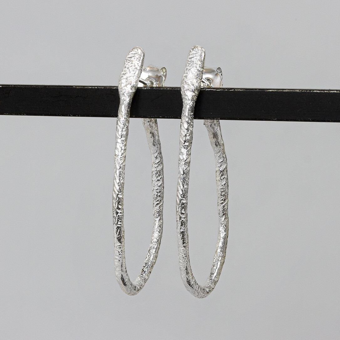 Hoepeloorbel van de najaarscollectie 2022 van Jéh Jewels geheel zilver. Deze oorbel is klassiek met een vleugje creativiteit. De vorm is wat speelser dan de klassieke hoepel en ook de afwerking is wat ruwer. Ondanks dat is het een oorbel voor elke gelegenheid.